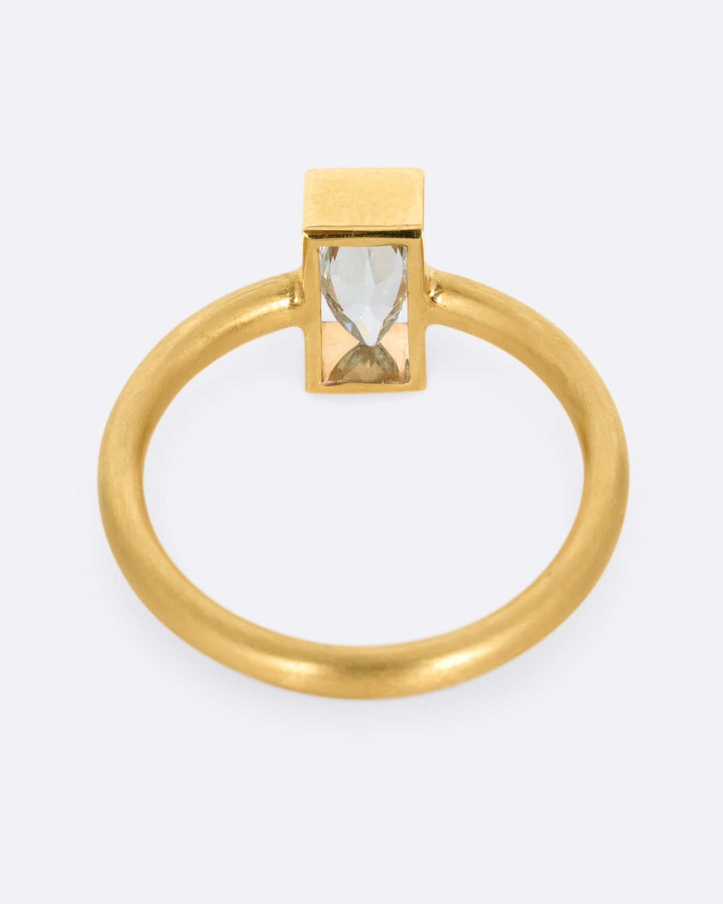 A yellow gold ring with an aquamarine in an open rectangular setting. Shown from the back.