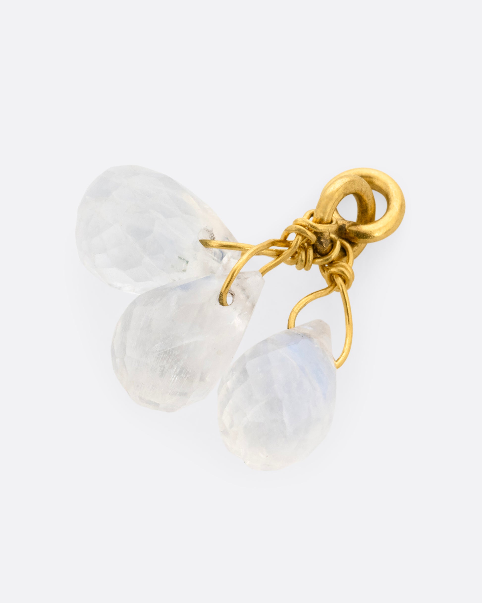 A yellow gold earring dangle with a trio of moonstone briolettes, shown lying on its side.