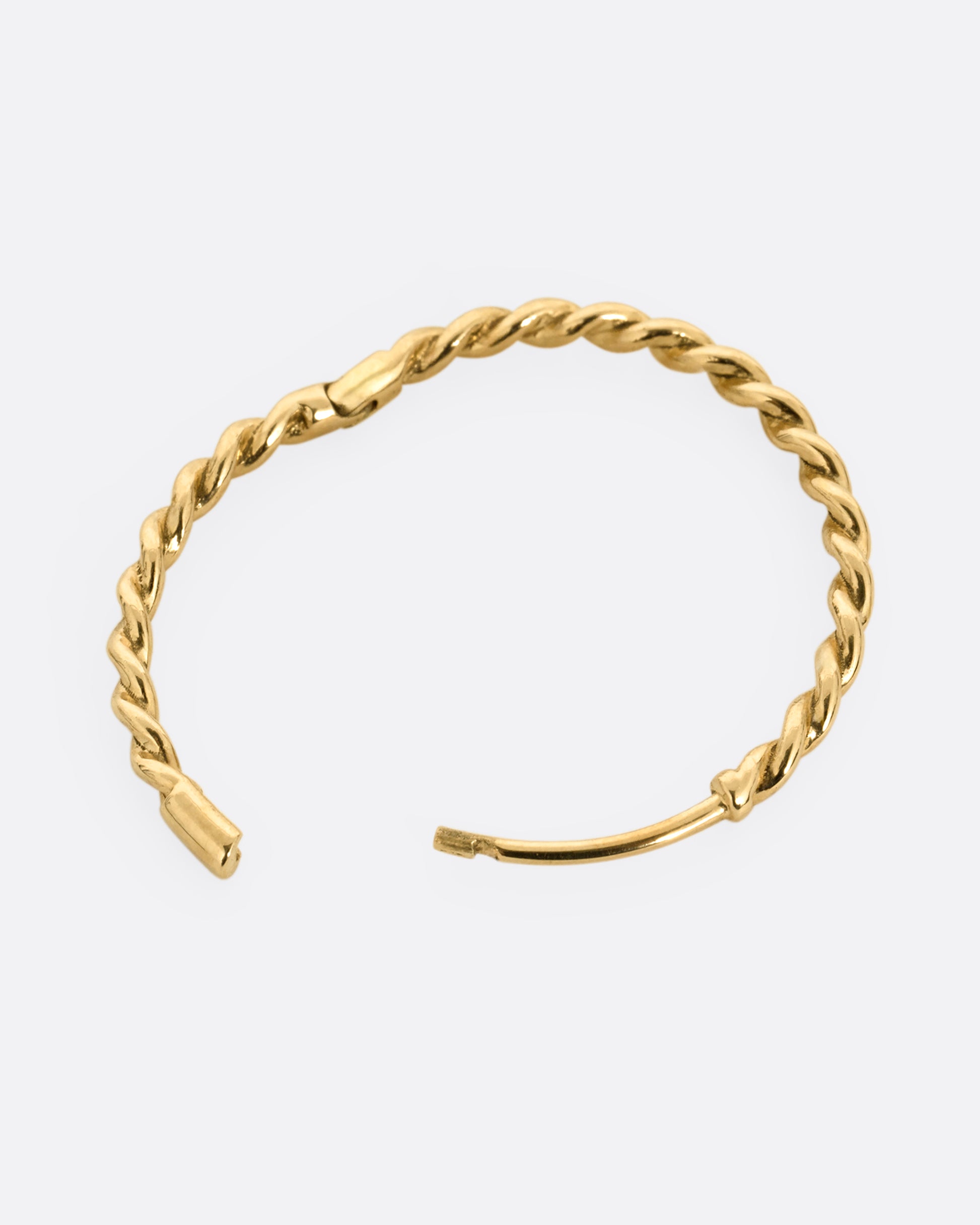A yellow gold twisted hoop earring with a clicker clasp, shown from the side open.
