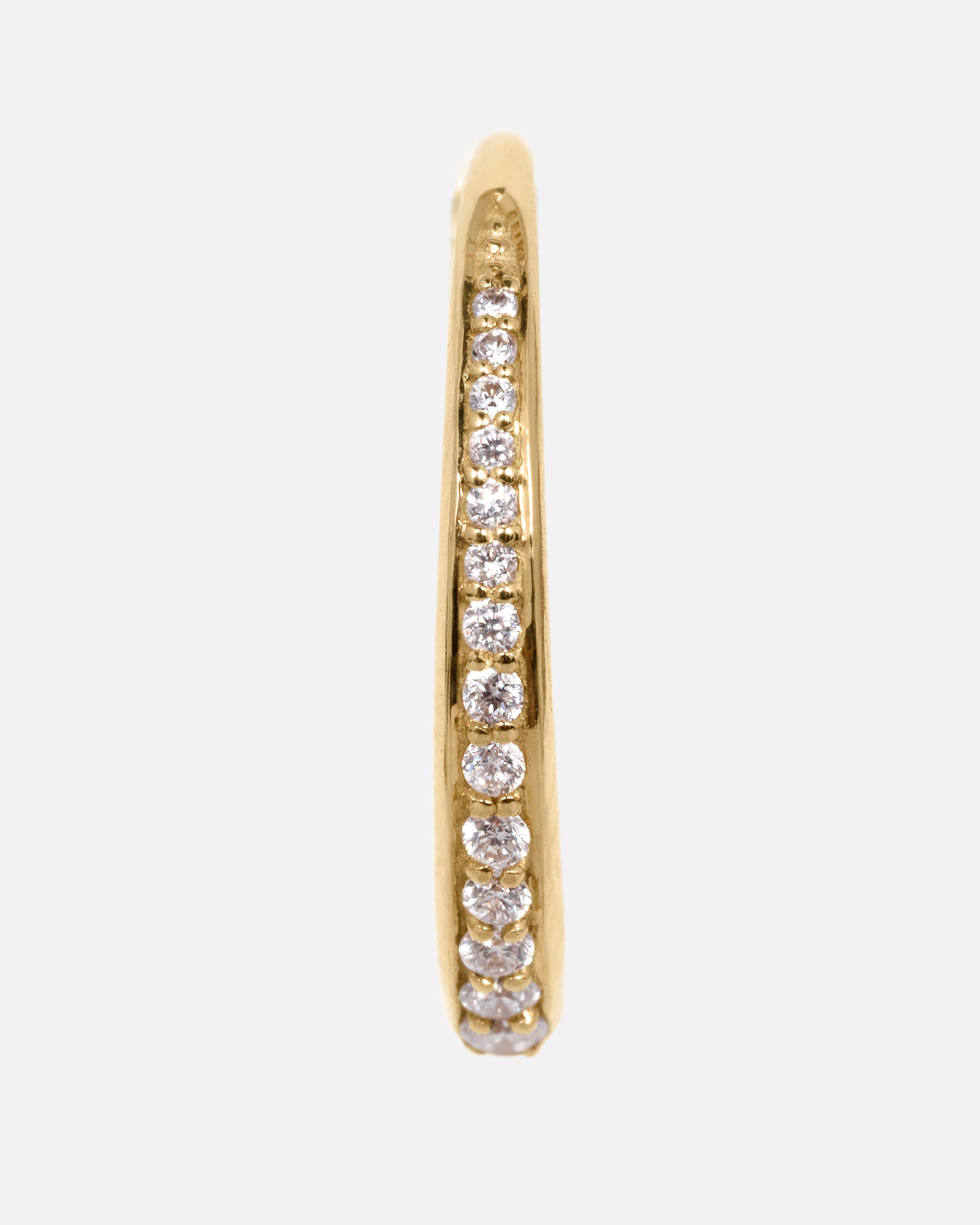 A yellow gold tapered hoop with a queue of graduated diamonds. Shown from the front standing up.