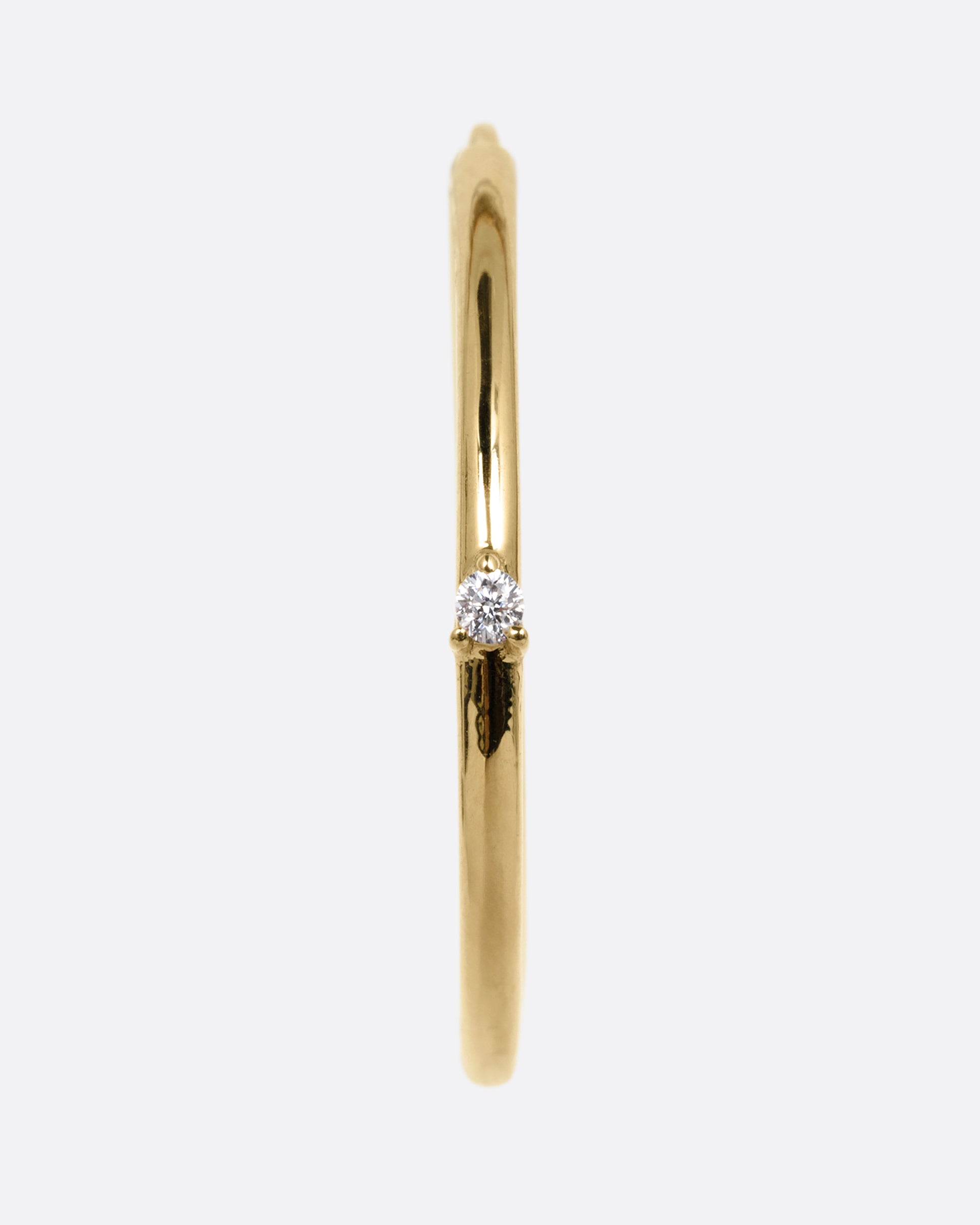 A yellow gold hoop earring with a tiny prong set diamond, shown from the front.