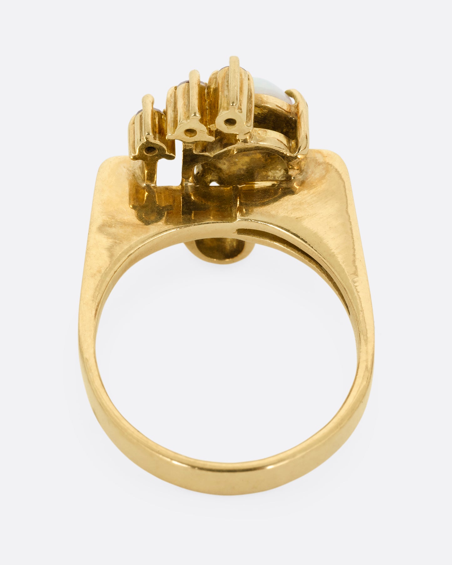 A yellow gold ring with a trio of diamonds, two Deco- inspired arches, and a prong set opal. Shown from the back.