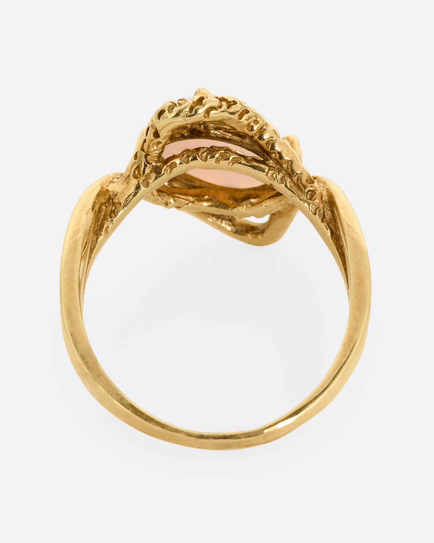 A yellow gold ring with two contrasting bands of polished and textured gold with an oval opal at the center. Shown from the back.