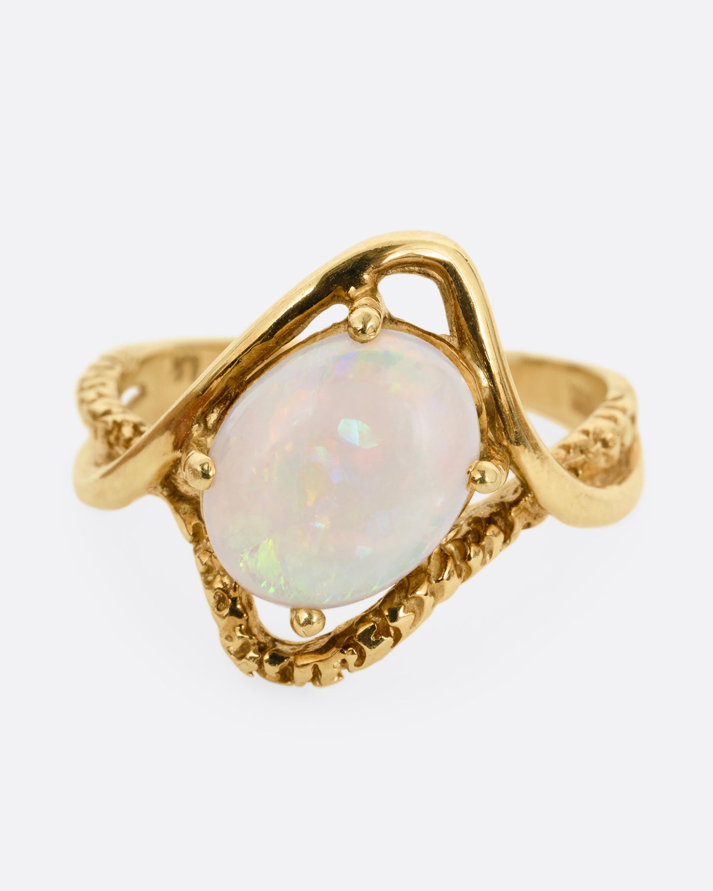 A yellow gold ring with two contrasting bands of polished and textured gold with an oval opal at the center. Shown from the front.