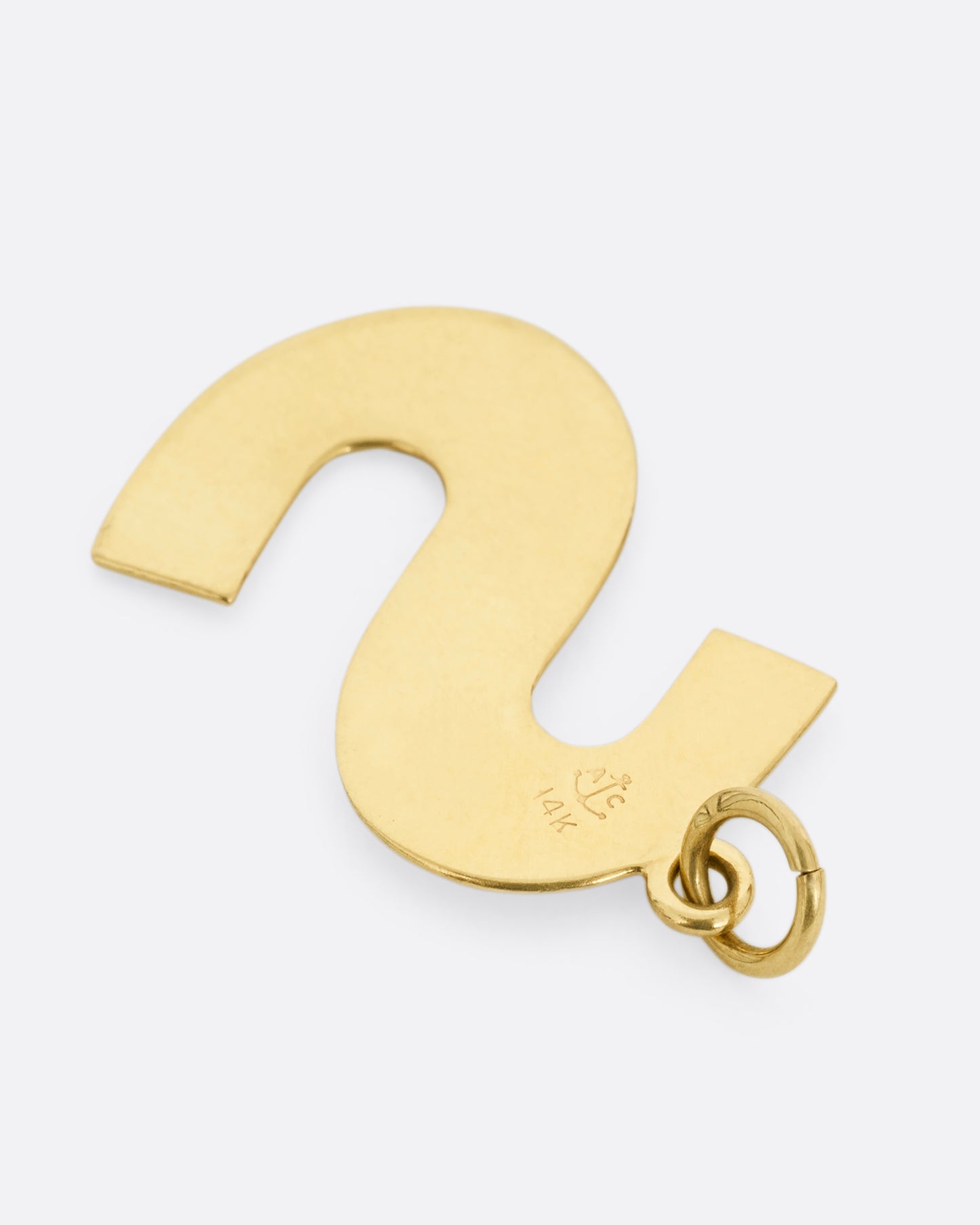 A yellow gold sans serif letter 's' pendant, shown from the back.