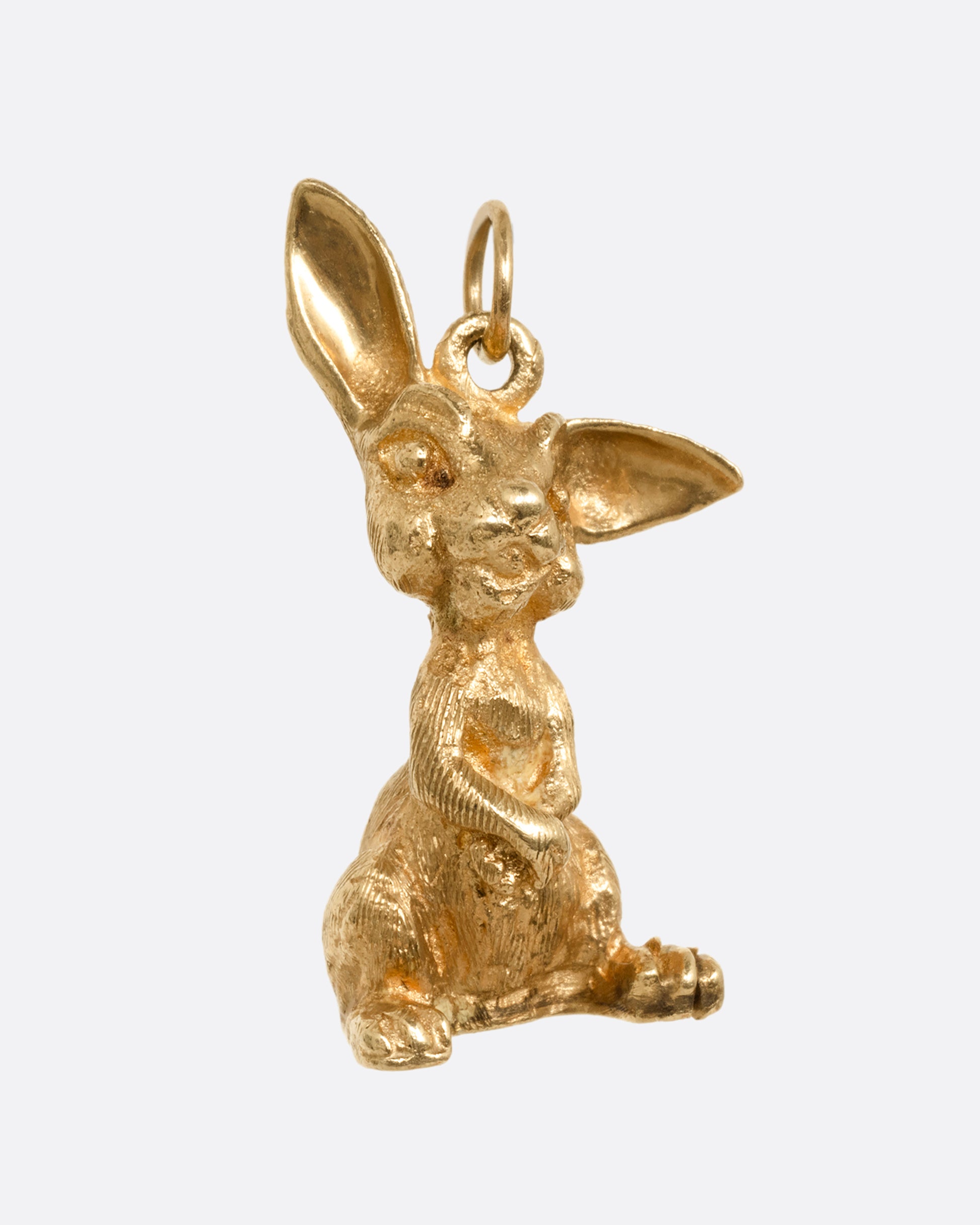 A yellow gold rabbit charm with one ear perked, sitting up. Shown from the front.