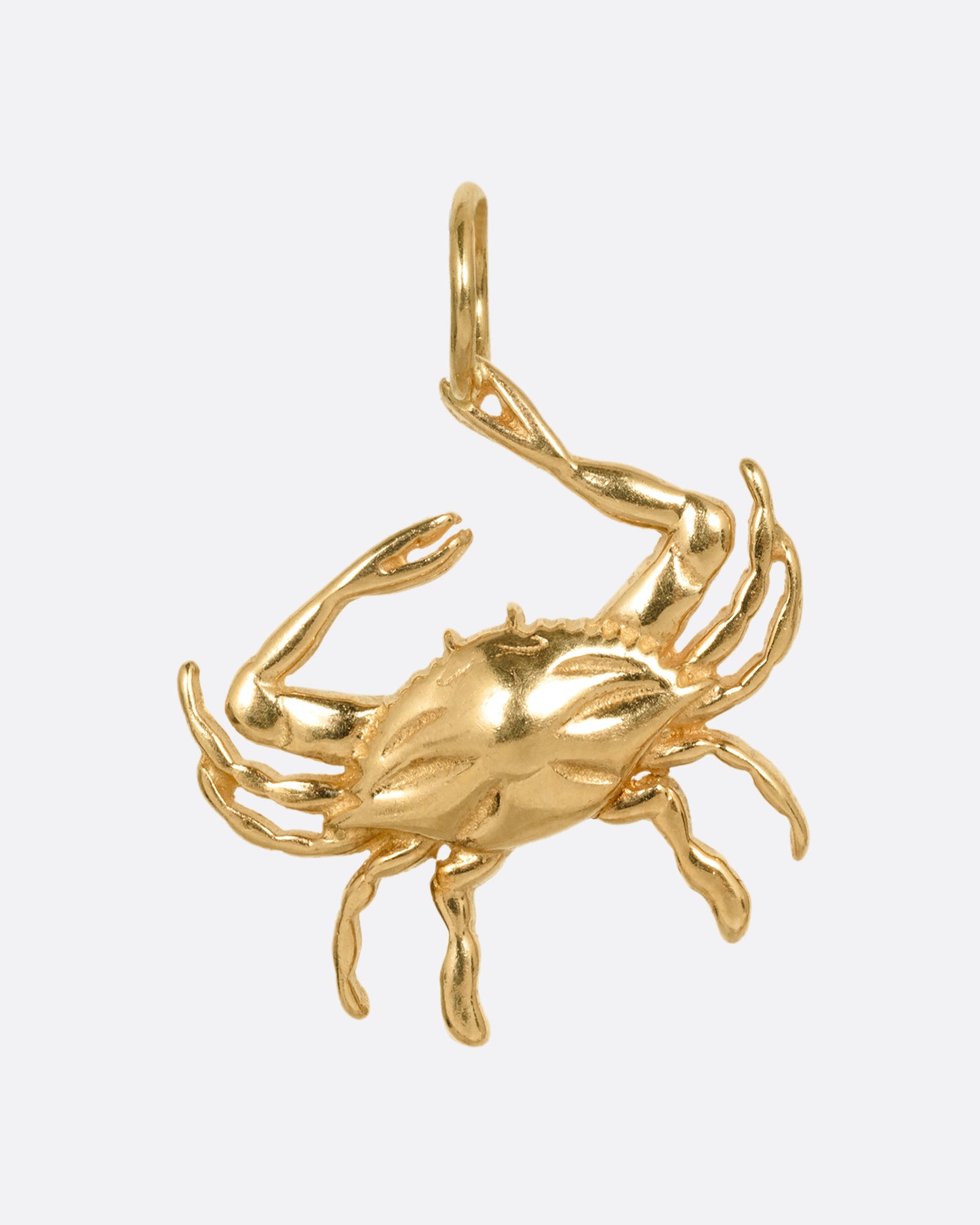 A yellow gold crab pendant grasping onto a jump ring with one claw. Shown from the front.