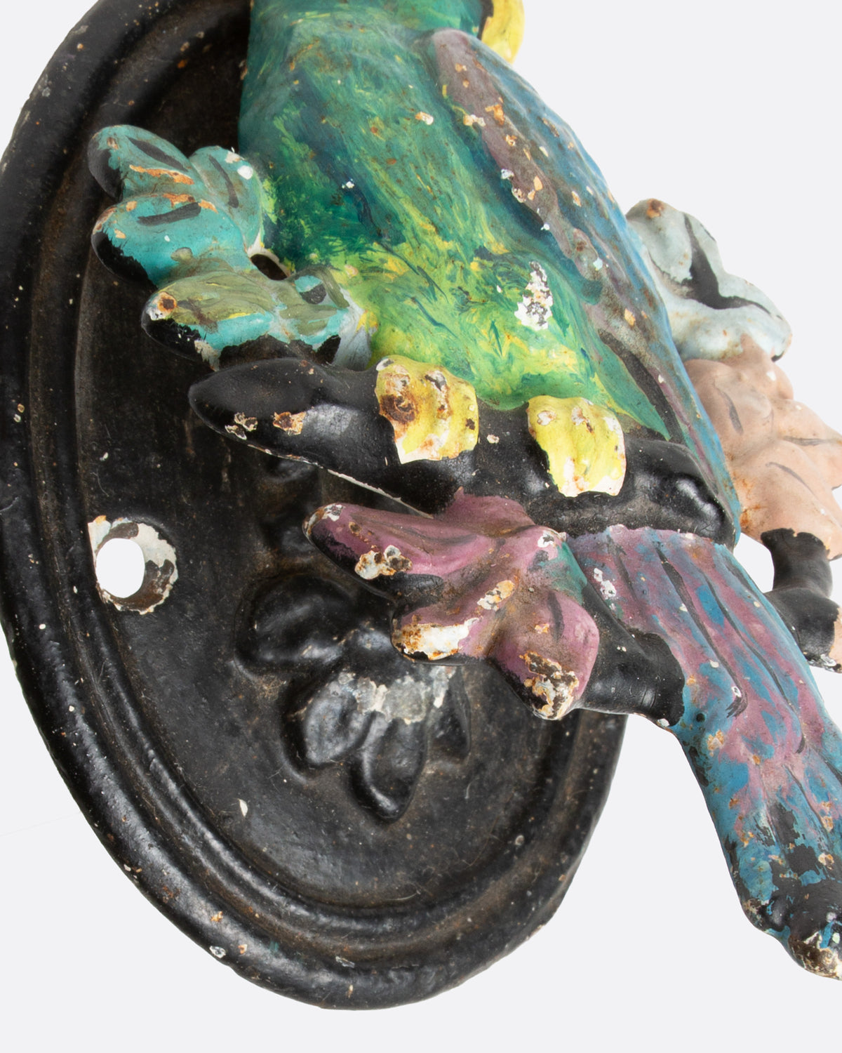 A close up of an iron parrot door knocker painted in bright colors.