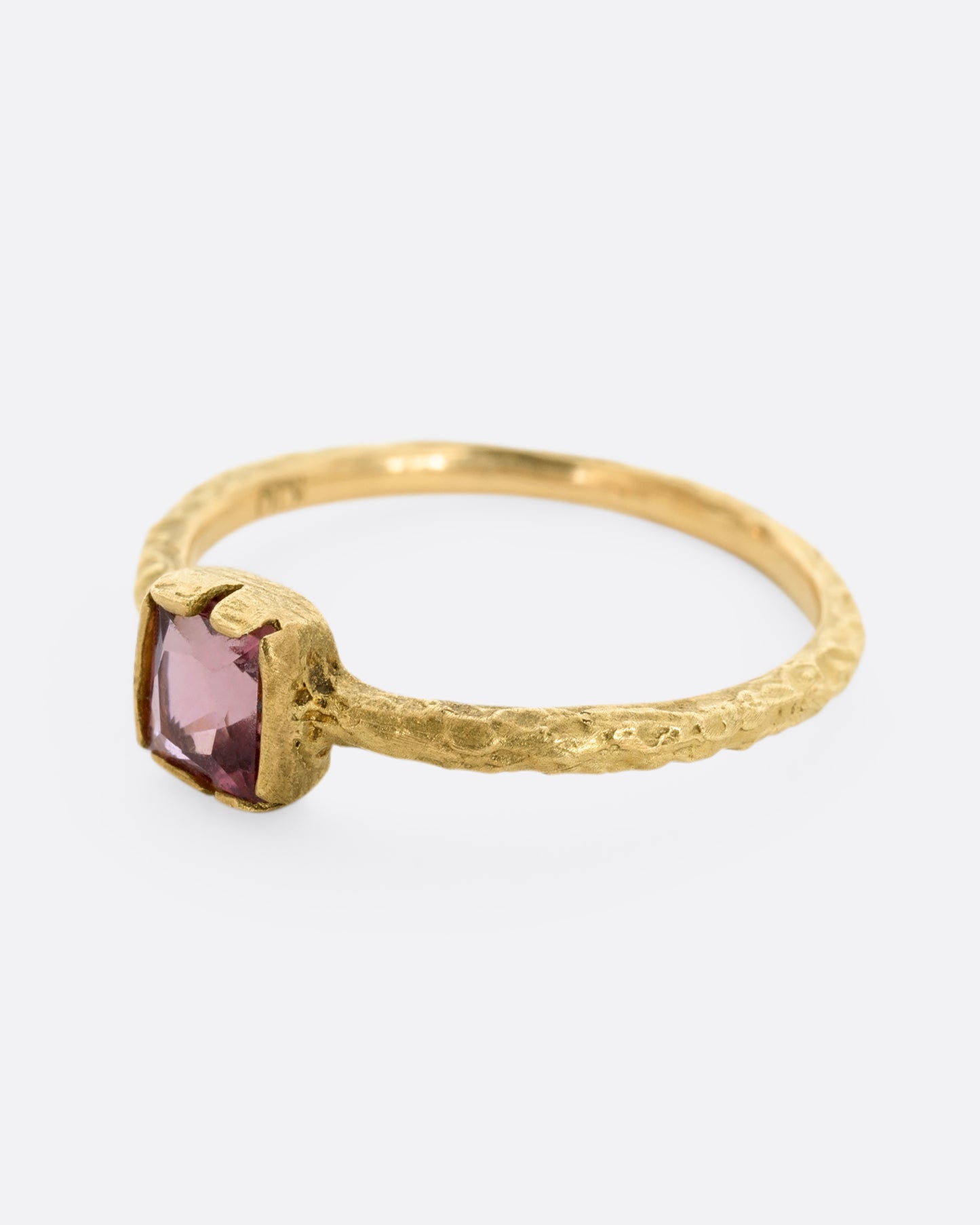 A textured yellow gold ring with a square pink tourmaline. Shown from the side.