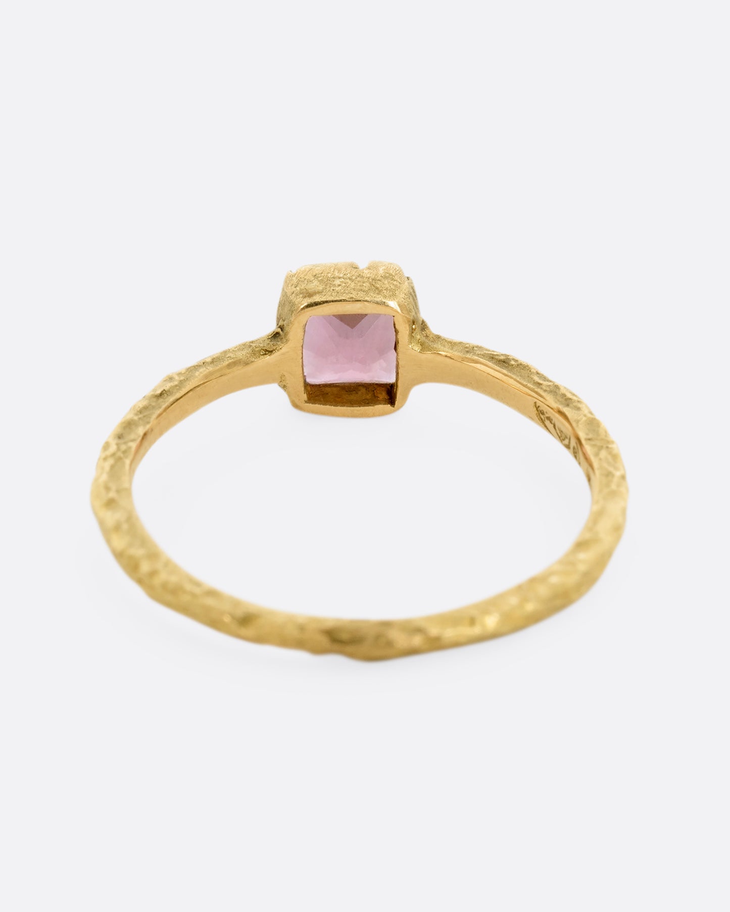 A textured yellow gold ring with a square pink tourmaline. Shown from the back.