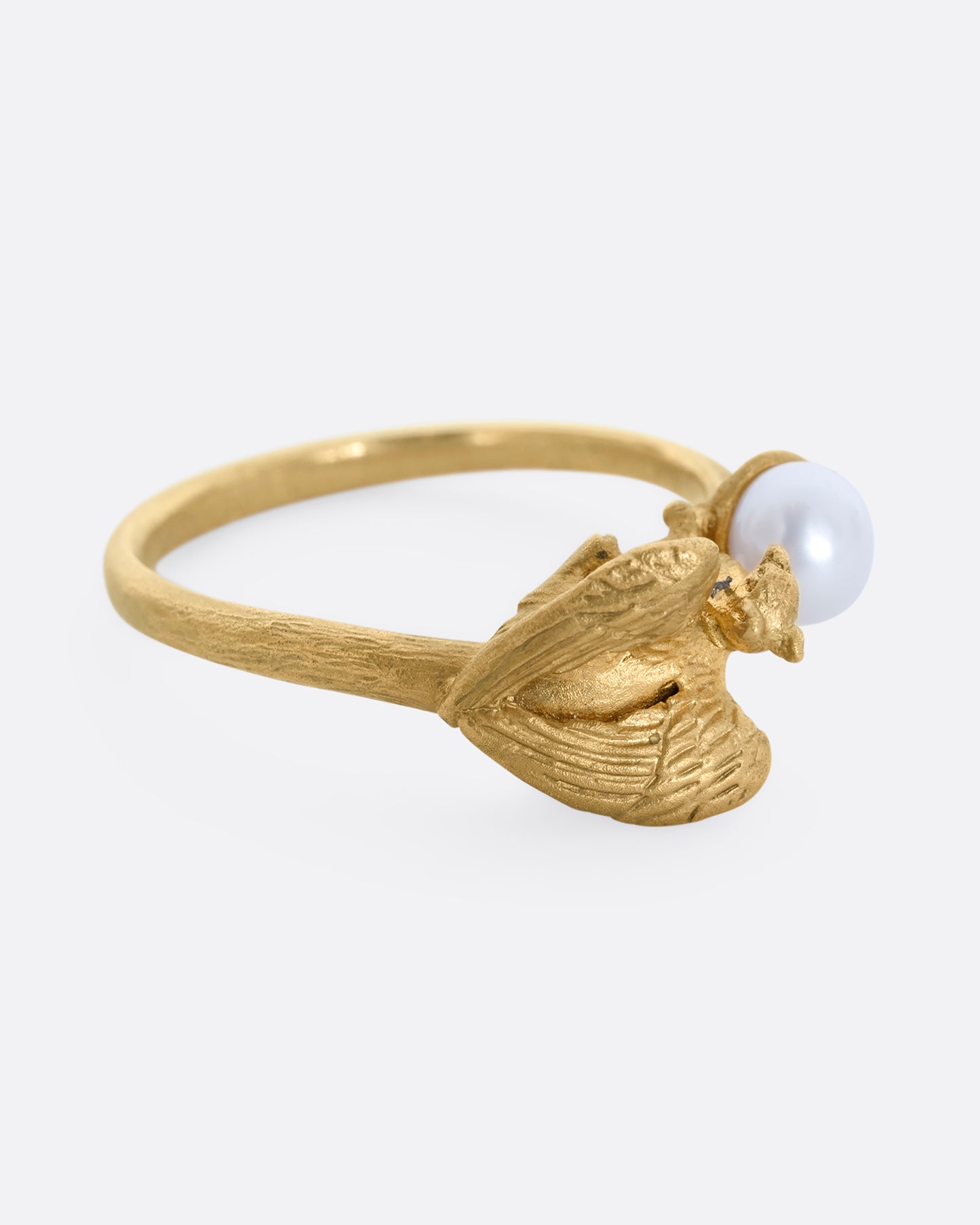 A yellow gold ring with a gryphon and a pearl. Shown laying flat.