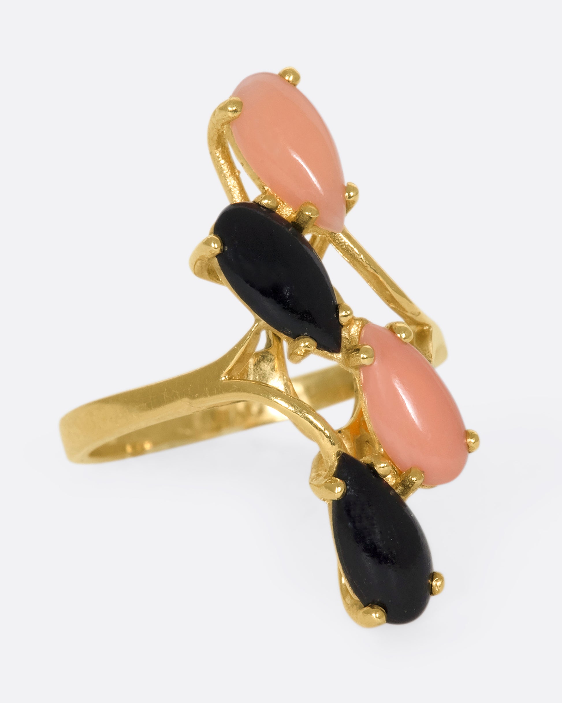 This vintage 14k gold ring features pear shaped coral and onyx cabochons that climb and elongate your finger.