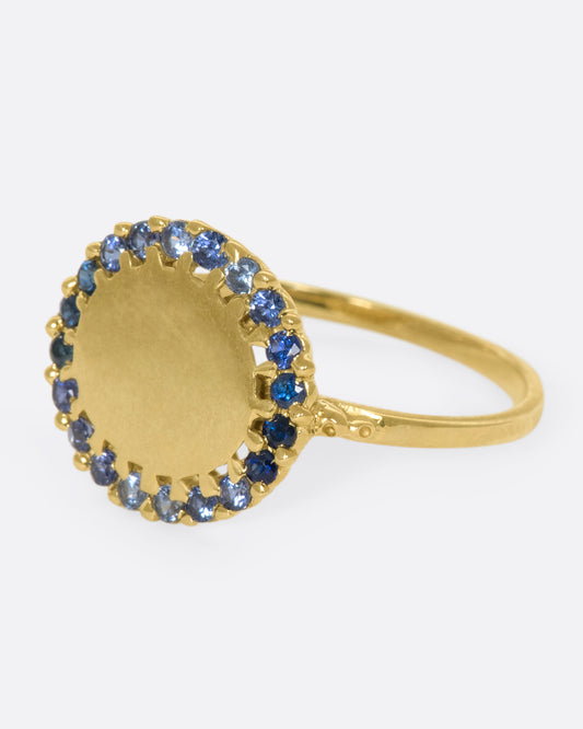 A 14k gold circle ring with a halo of ombré blue sapphires
