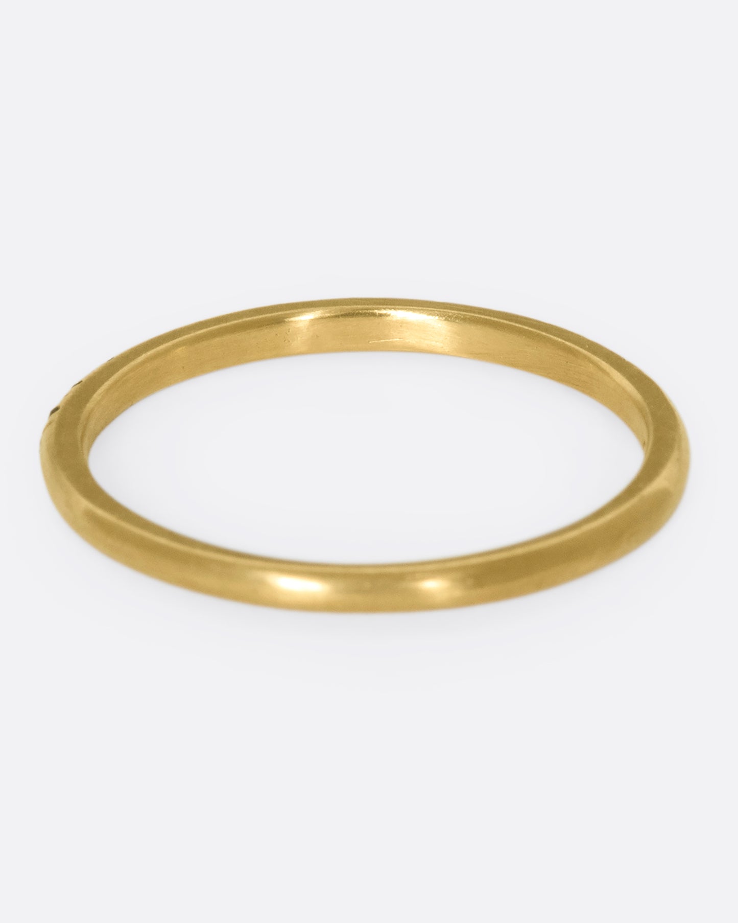 A thin yellow gold band with three green garnets set in the middle and five blue sapphires on either side. Shown from the back.