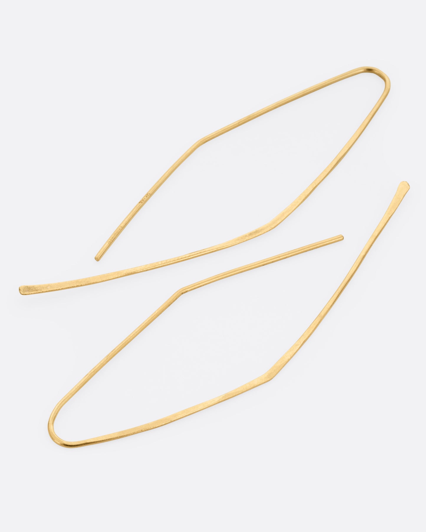A pair of yellow gold angular hammered hook earrings. Shown lying flat from the side.