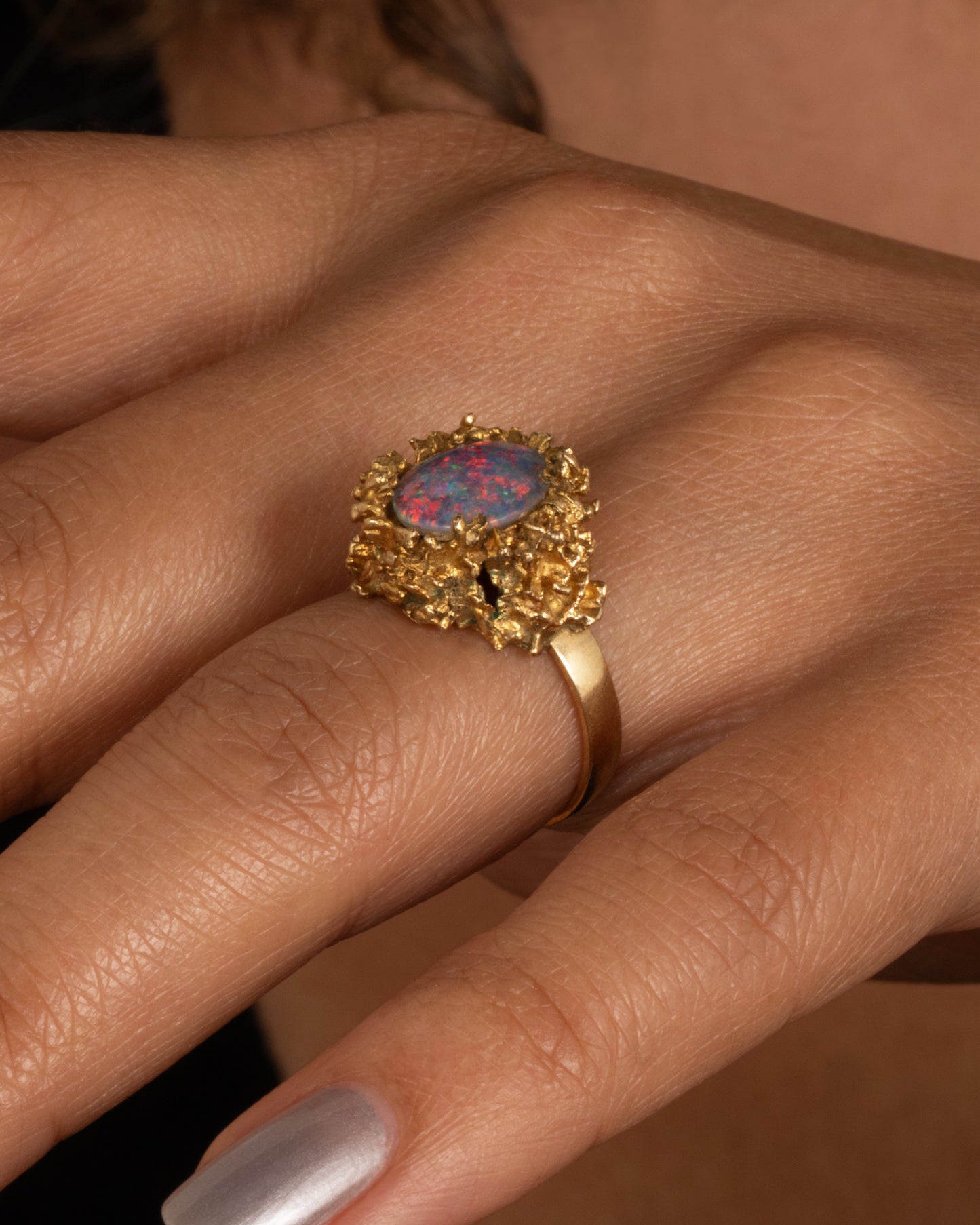 A yellow gold Brutalist era statement ring with an opal doublet in a molten gold nest. Shown worn.