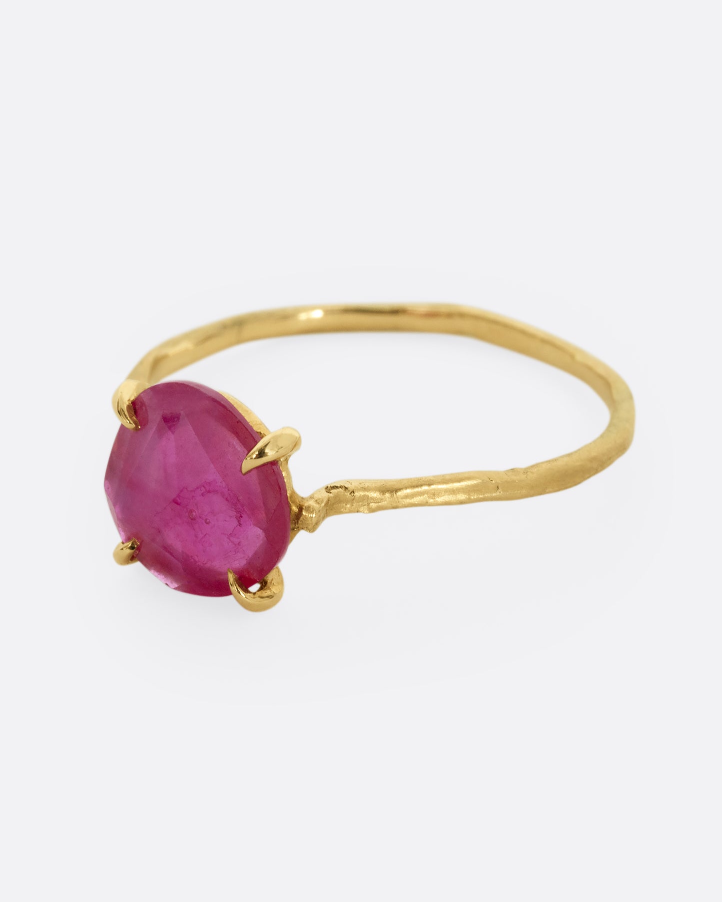A yellow gold ring with a prong set ruby. Shown from the side.
