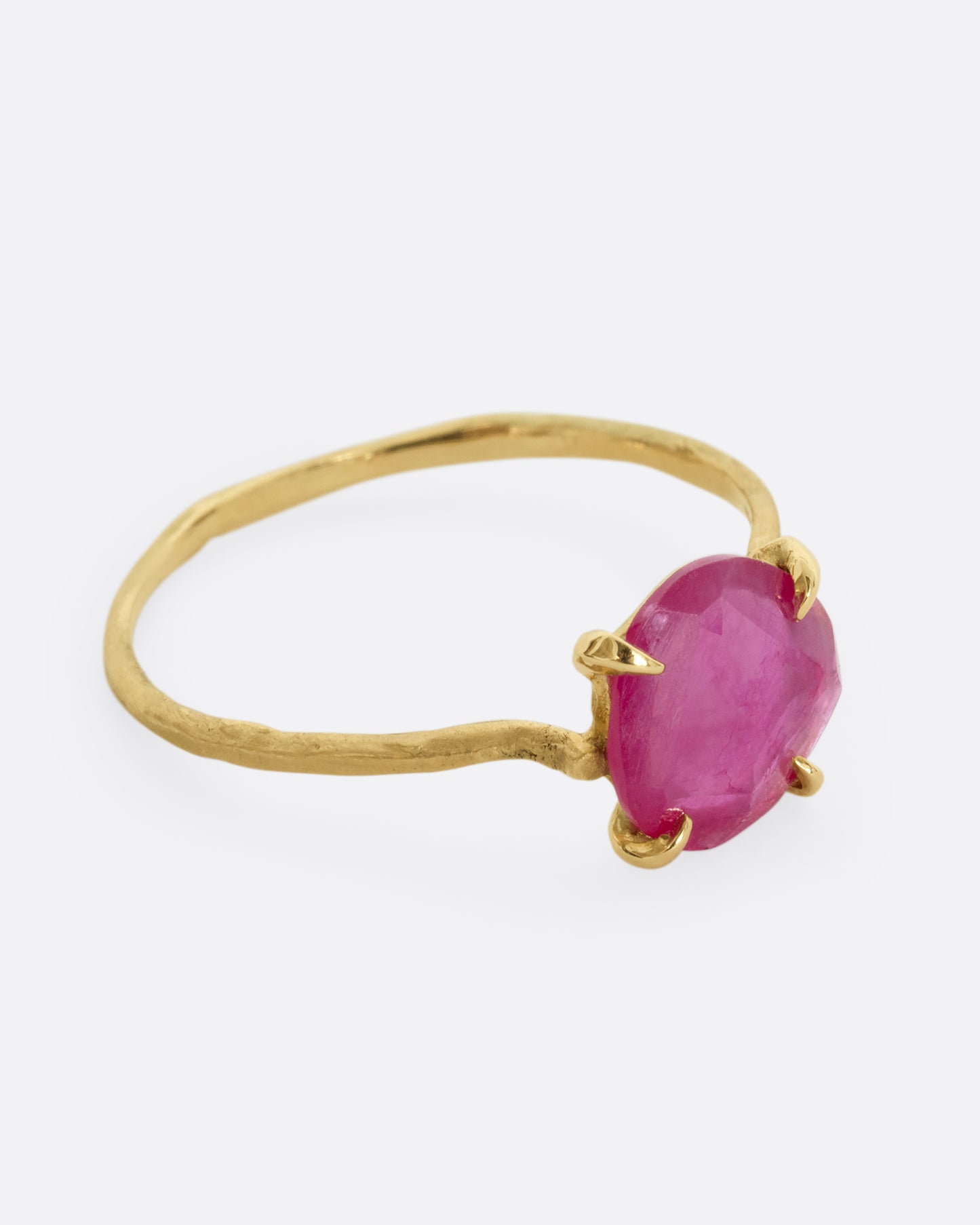 A yellow gold ring with a prong set ruby. Shown from the side.