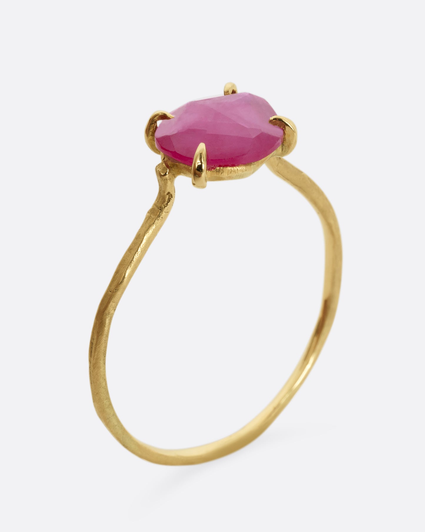 A yellow gold ring with a prong set ruby. Shown standing up from the side.