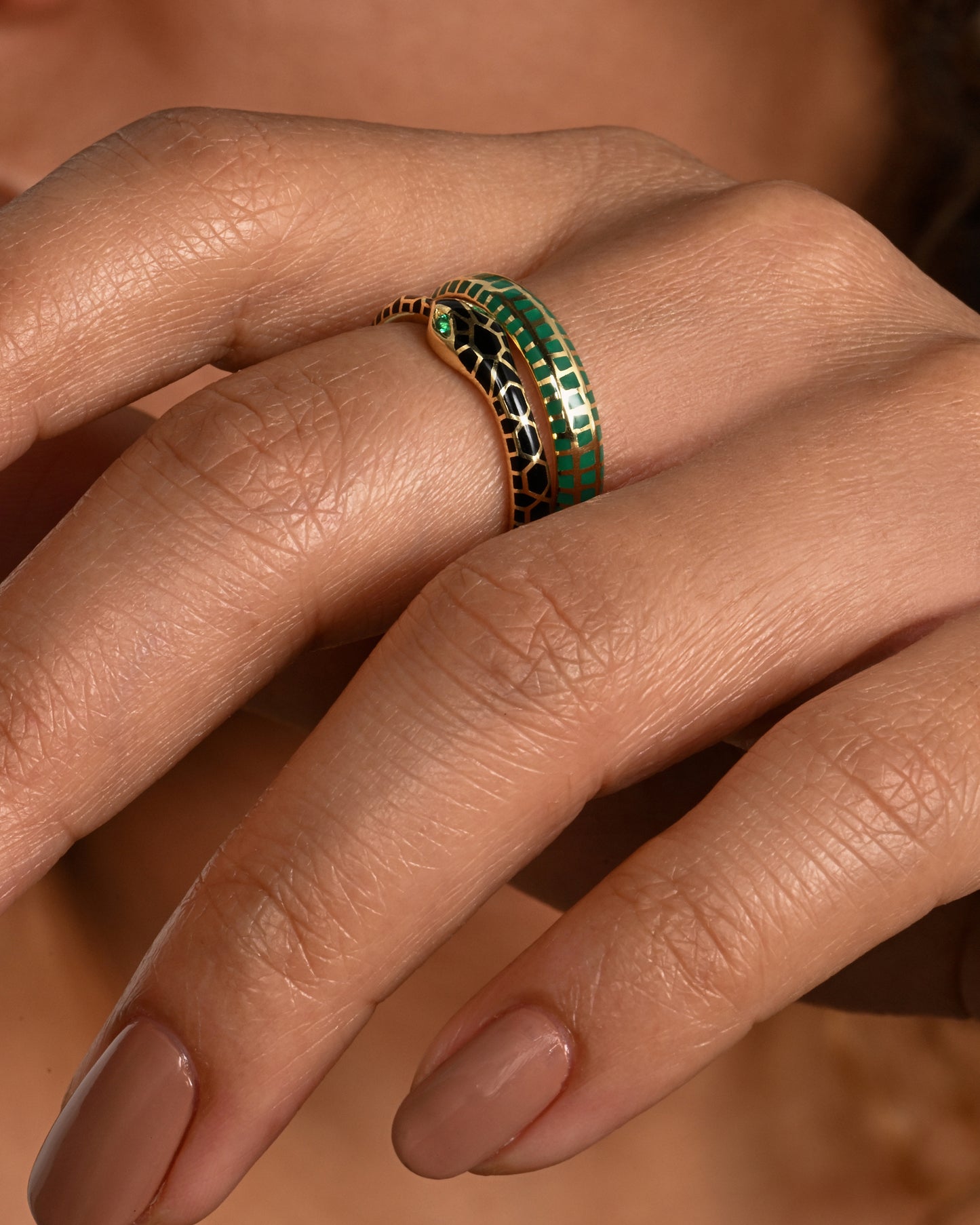 yellow gold ring with emerald and enamel shown on finger