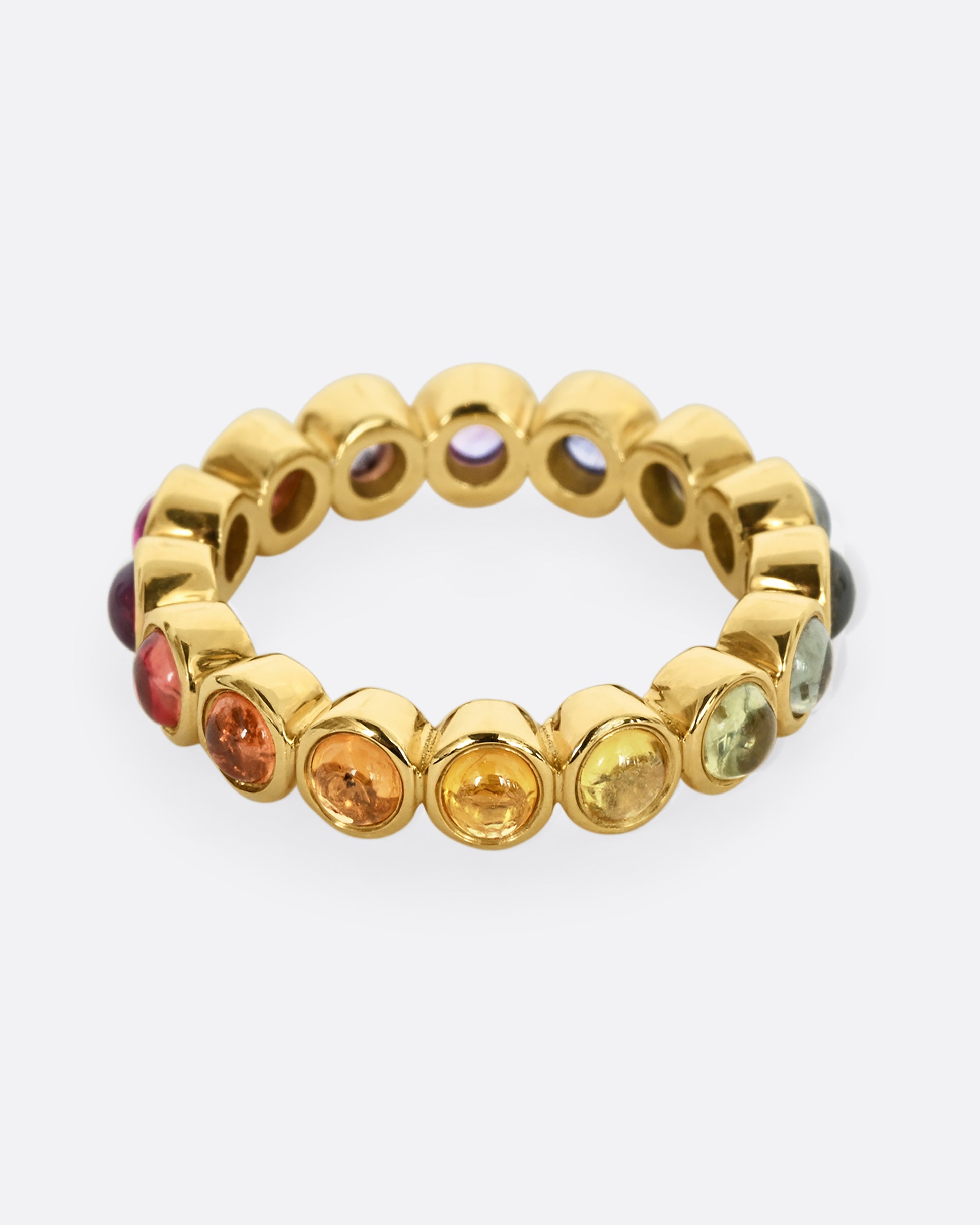 A yellow gold half eternity band with multicolor bezel set sapphire cabochons.