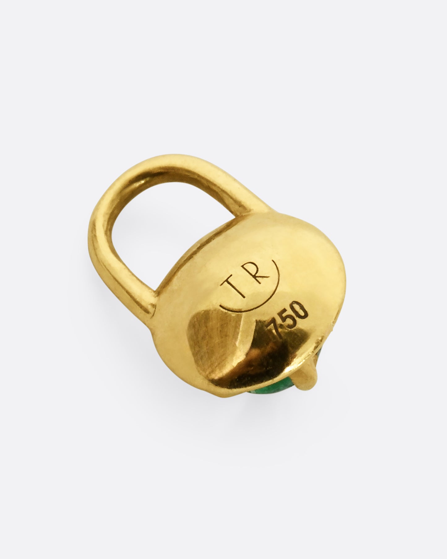 A yellow gold pendant in the shape of a lock with an emerald cabochon at the center. Shown laying flat.