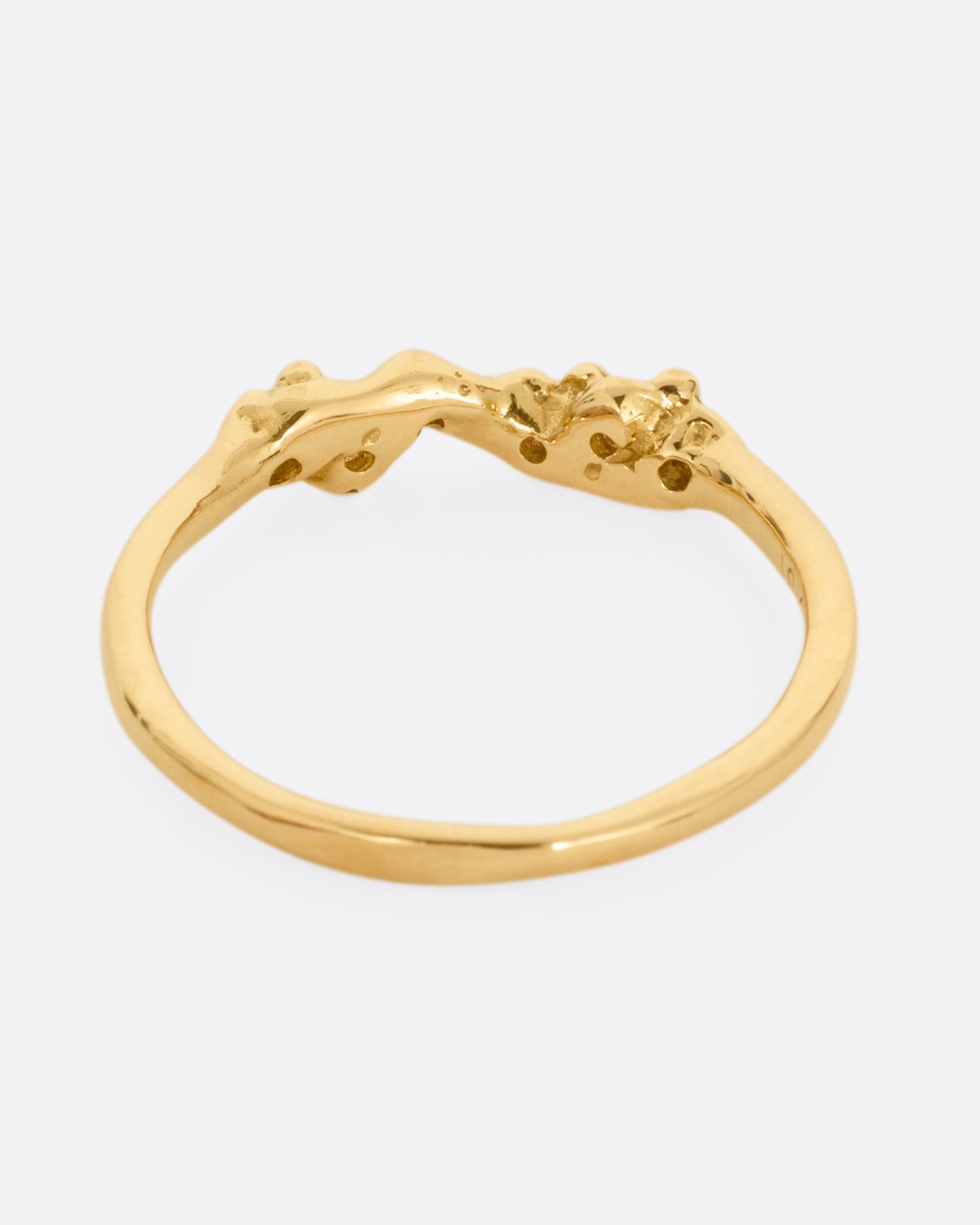 A yellow gold ring with a queue of diamonds set into a textural front. Shown from the back.