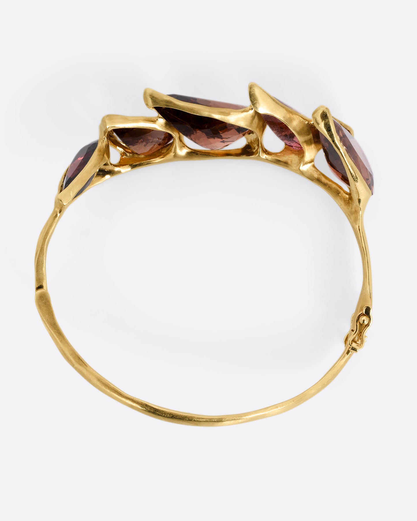 A bird's eye view of a yellow gold bracelet with five teardrop shaped tourmalines.