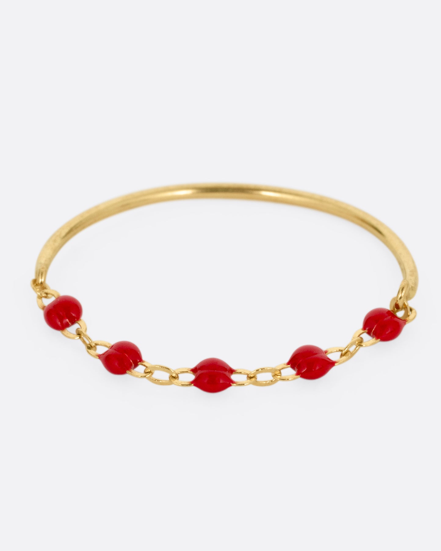 A yellow gold ring with a solid back and cable chain front with red resin droplets. Shown from the front.