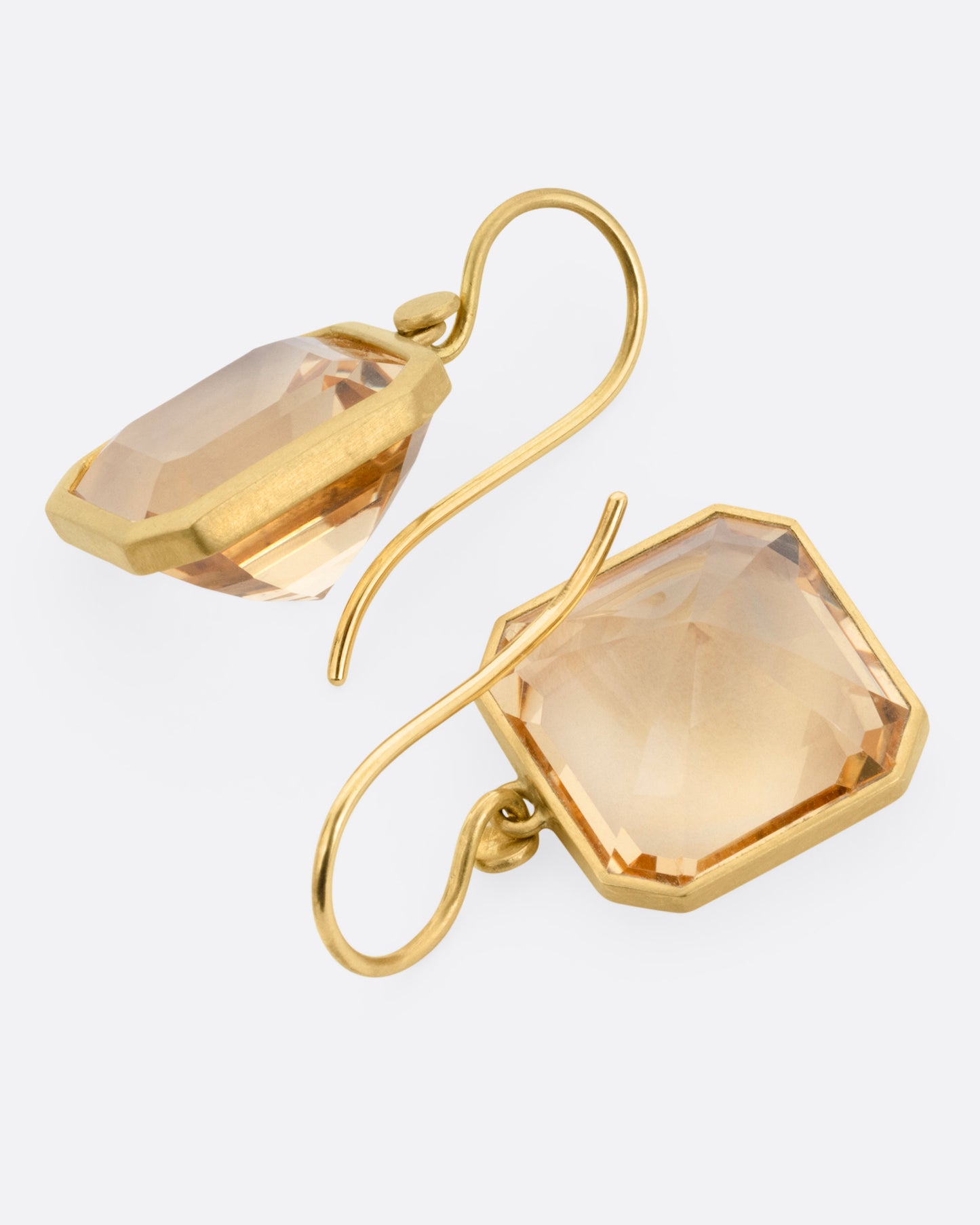 A pair of yellow gold drop earrings with octagonal citrines, shown lying flat.
