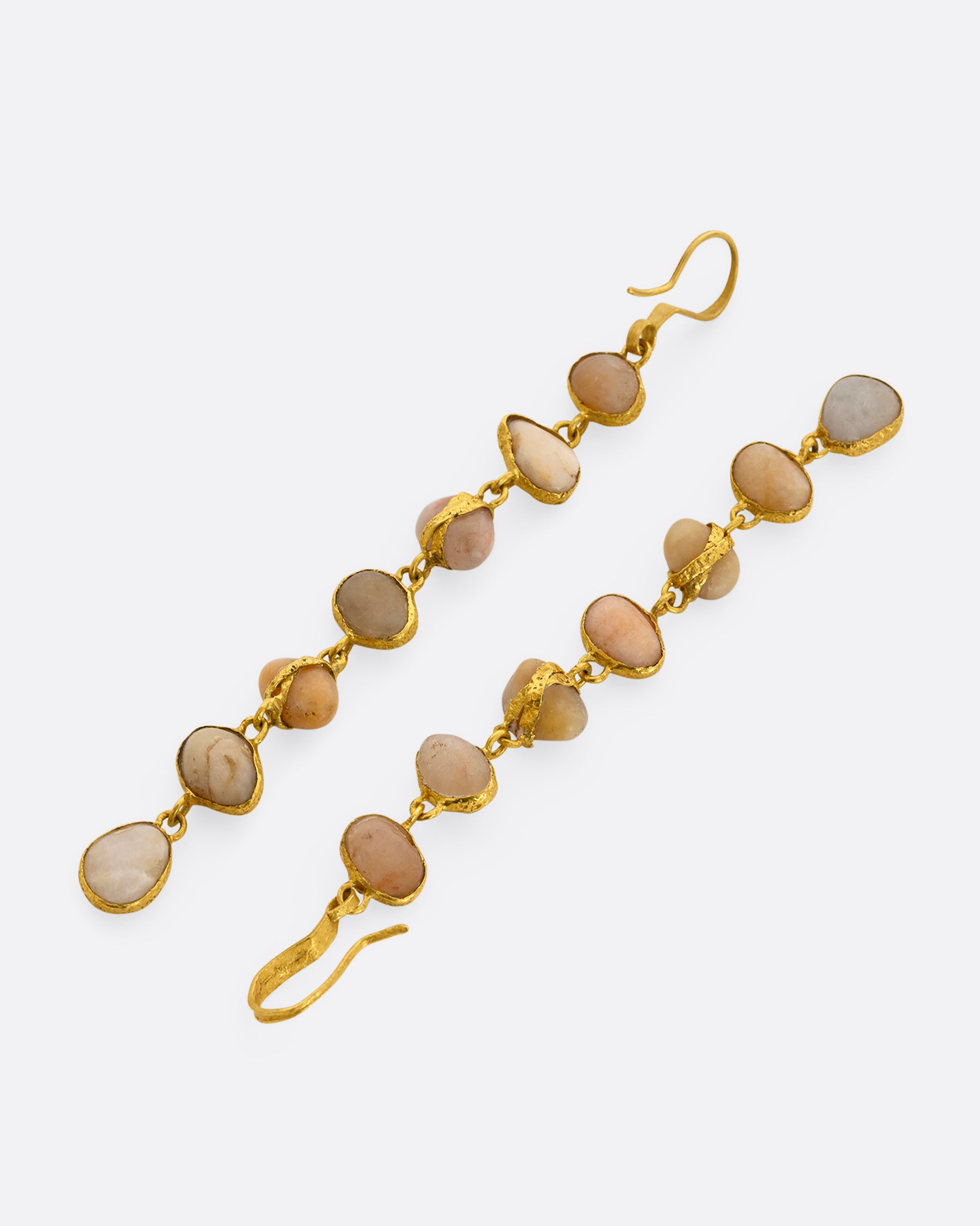 A pair of earrings with seven river pebbles, each wrapped in yellow gold hanging from yellow gold ear hooks. Shown from the front.