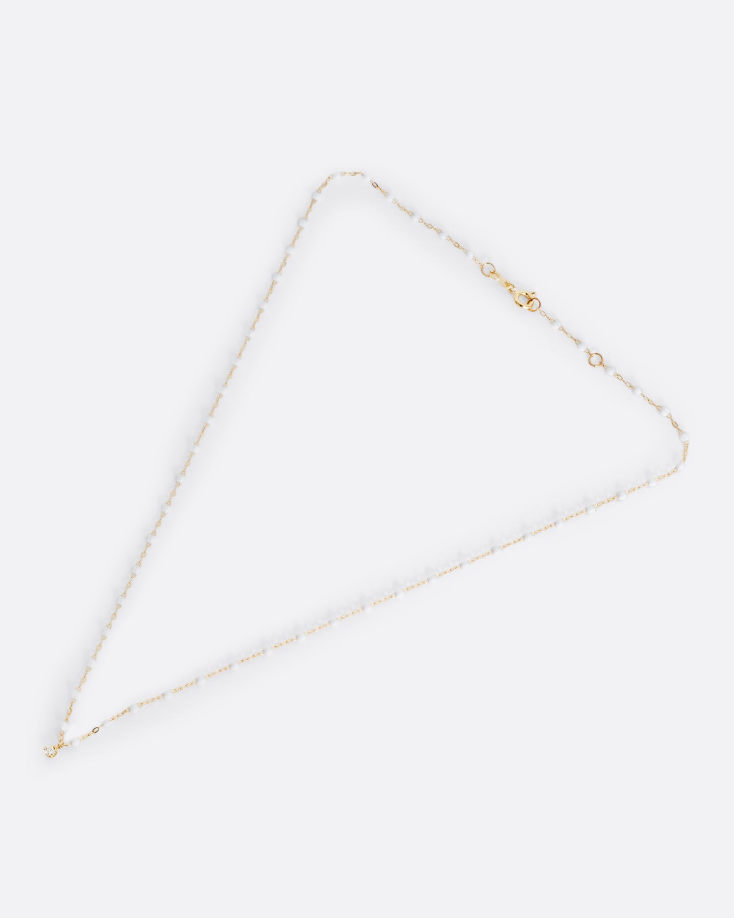 A yellow gold cable chain necklace with droplets of white resin and a single white diamond. Shown from the front.