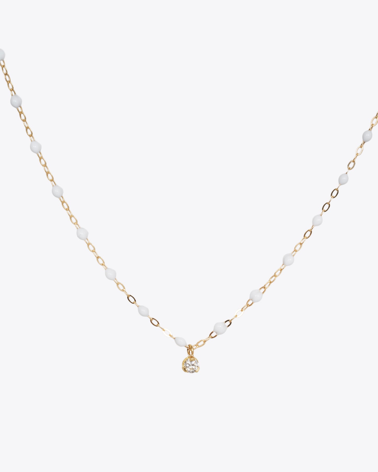 A yellow gold cable chain necklace with droplets of white resin and a single white diamond. Shown from the front.