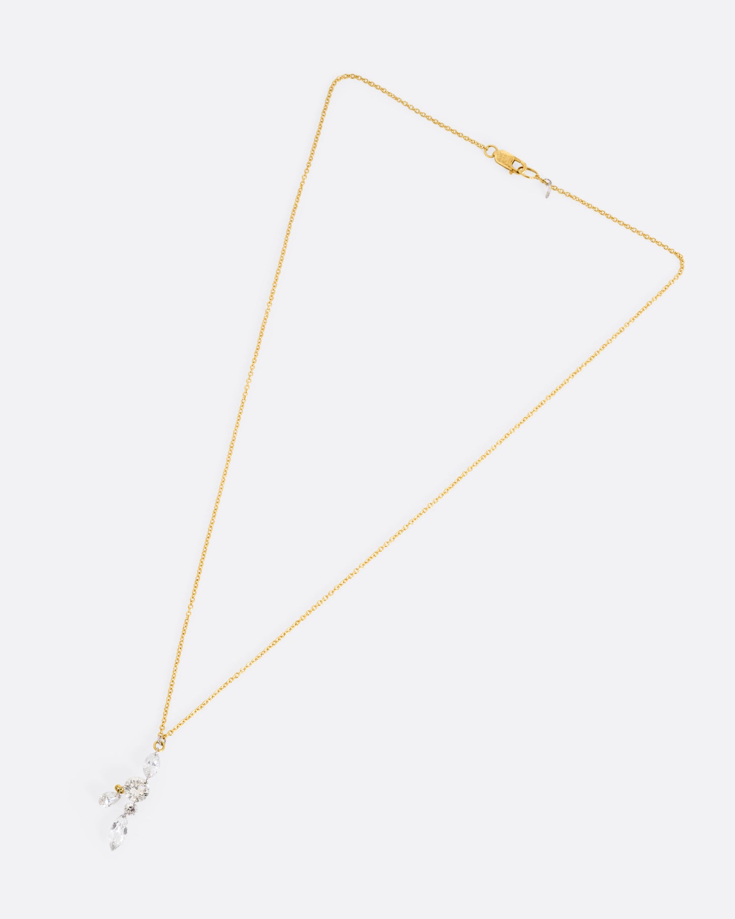 A yellow gold cable chain necklace with an arrangement of free set round, marquise, and pear shaped diamonds in platinum jump rings, shown from the front.
