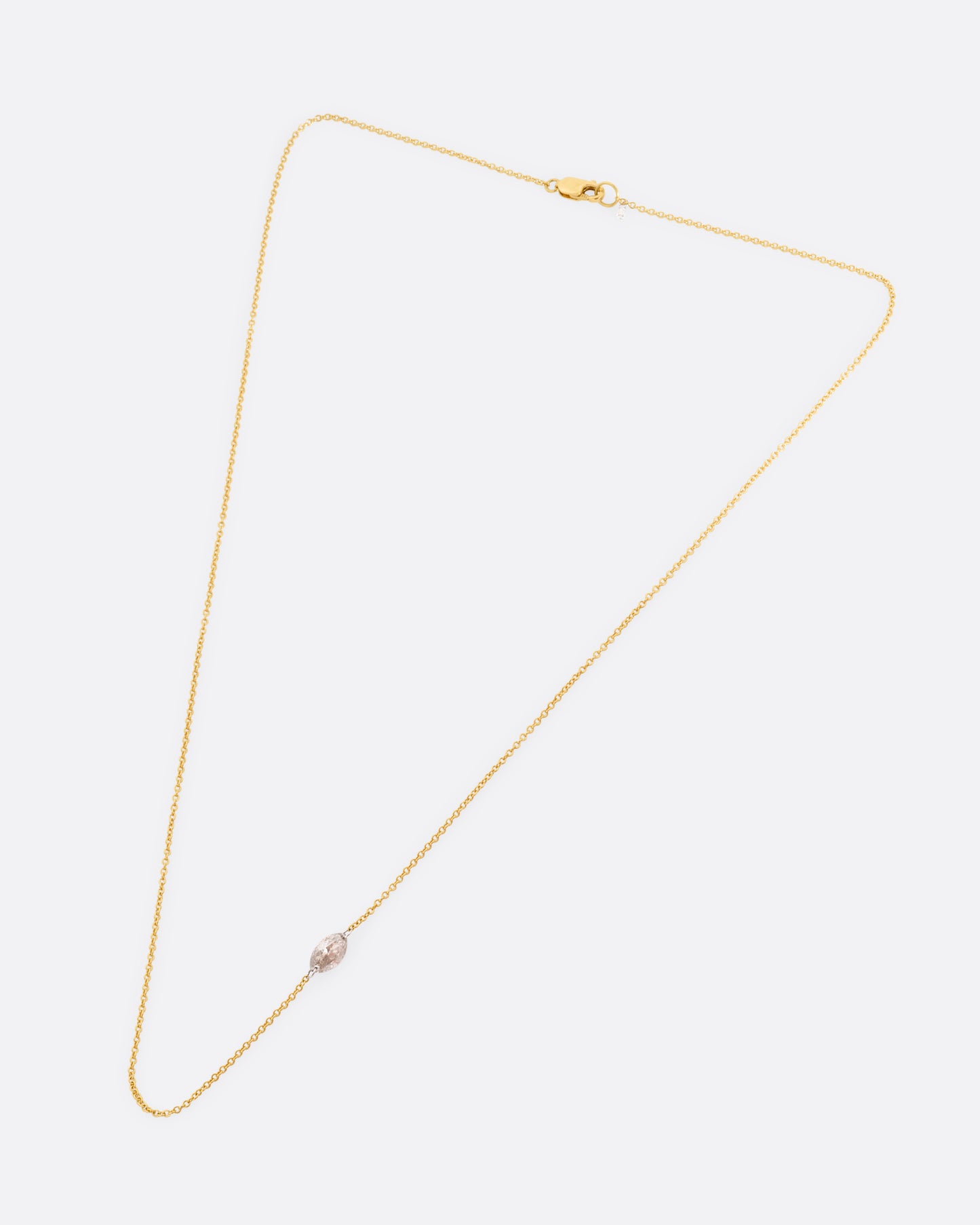 A yellow gold cable chain necklace with platinum jump rings and a free set marquise diamond, asymmetrically set. Shown from the front.