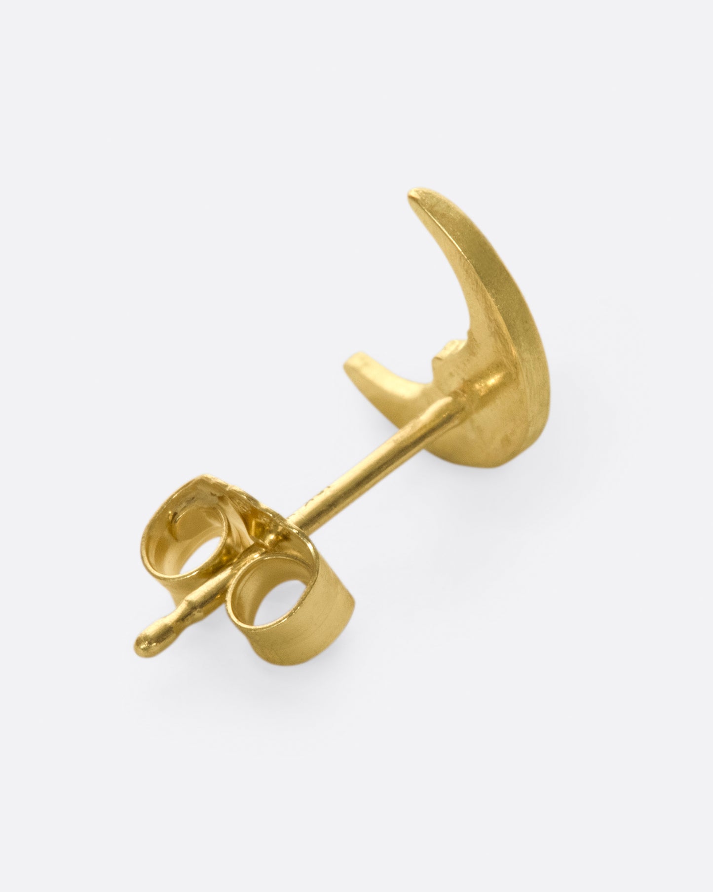 A yellow gold crescent moon stud earring with a face and a diamond eye. Shown from the back.