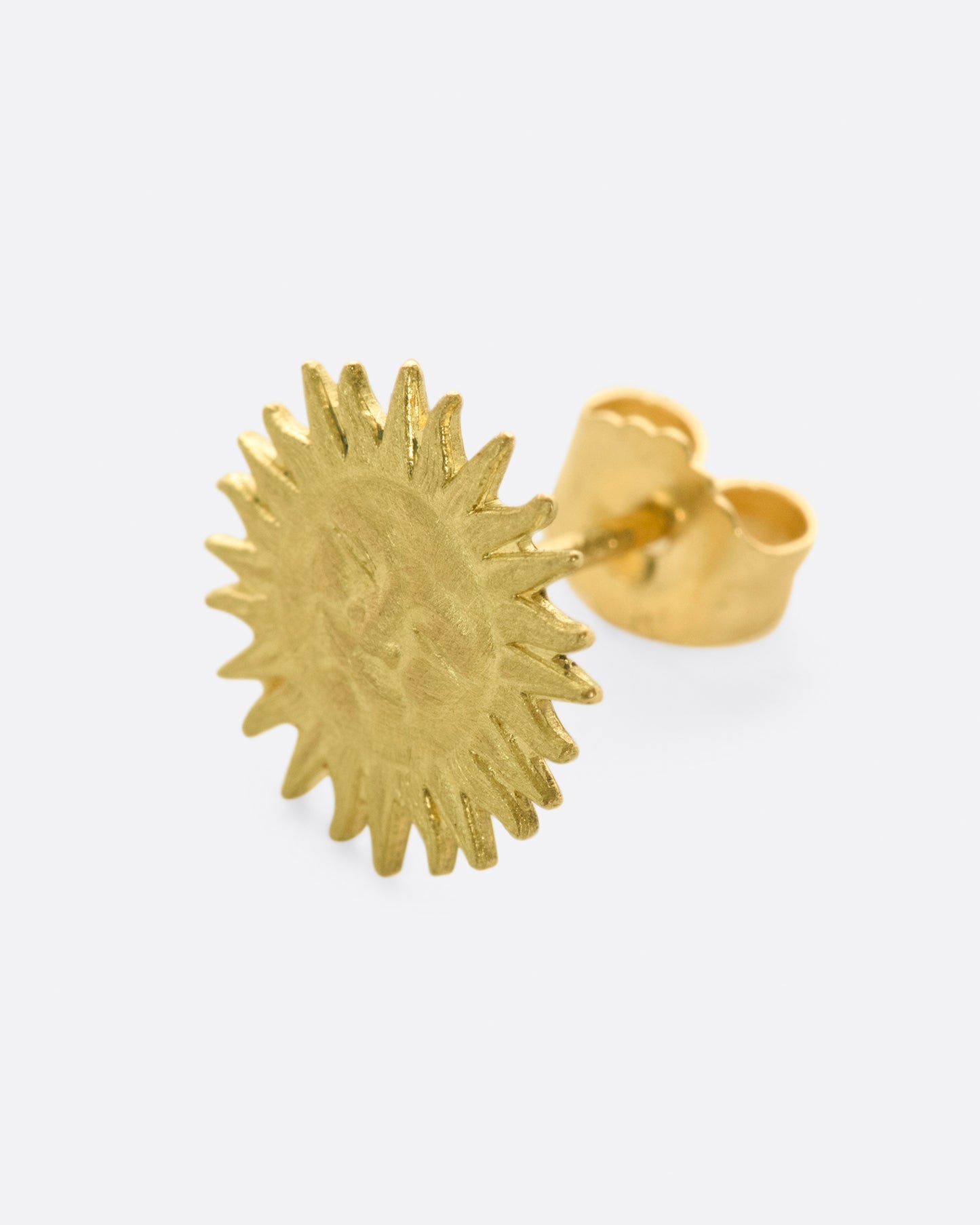 A yellow gold sun face stud earring. Shown from the front at an angle.