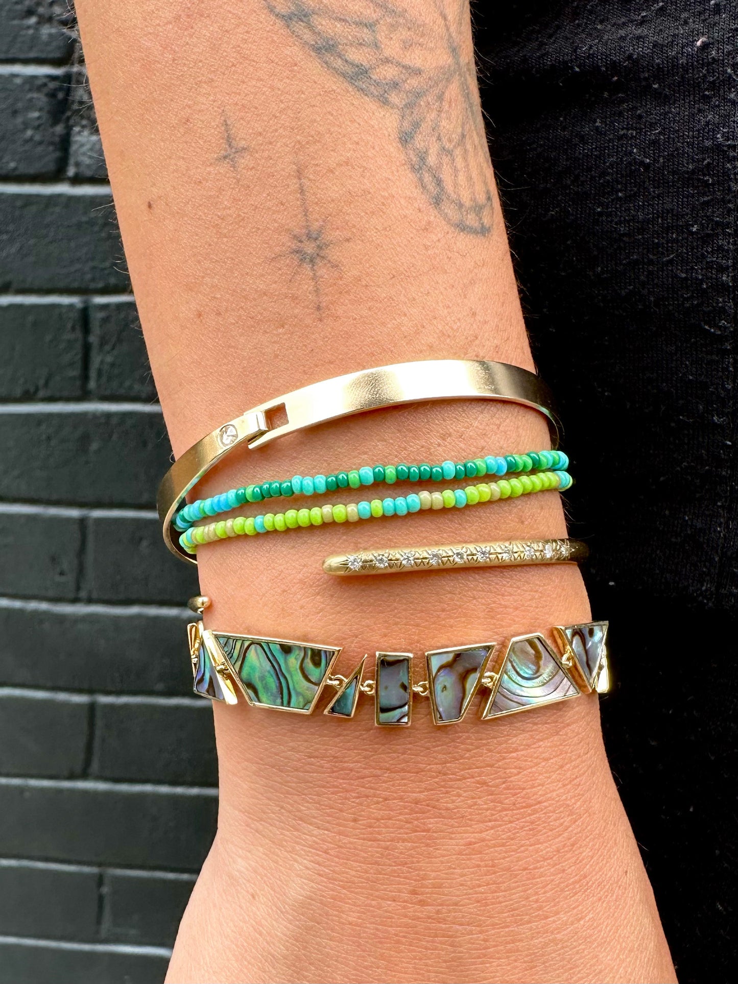 A wrist shown styled with five different bracelets.