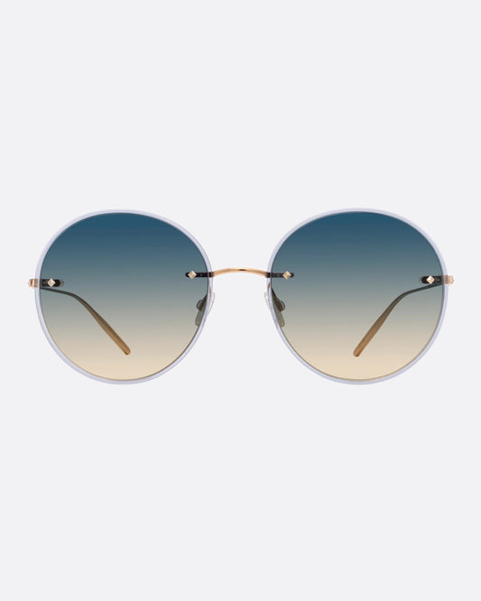 A pair of gold titanium sunglasses with large round blue to yellow ombré lenses with narrow light blue acetate frames.