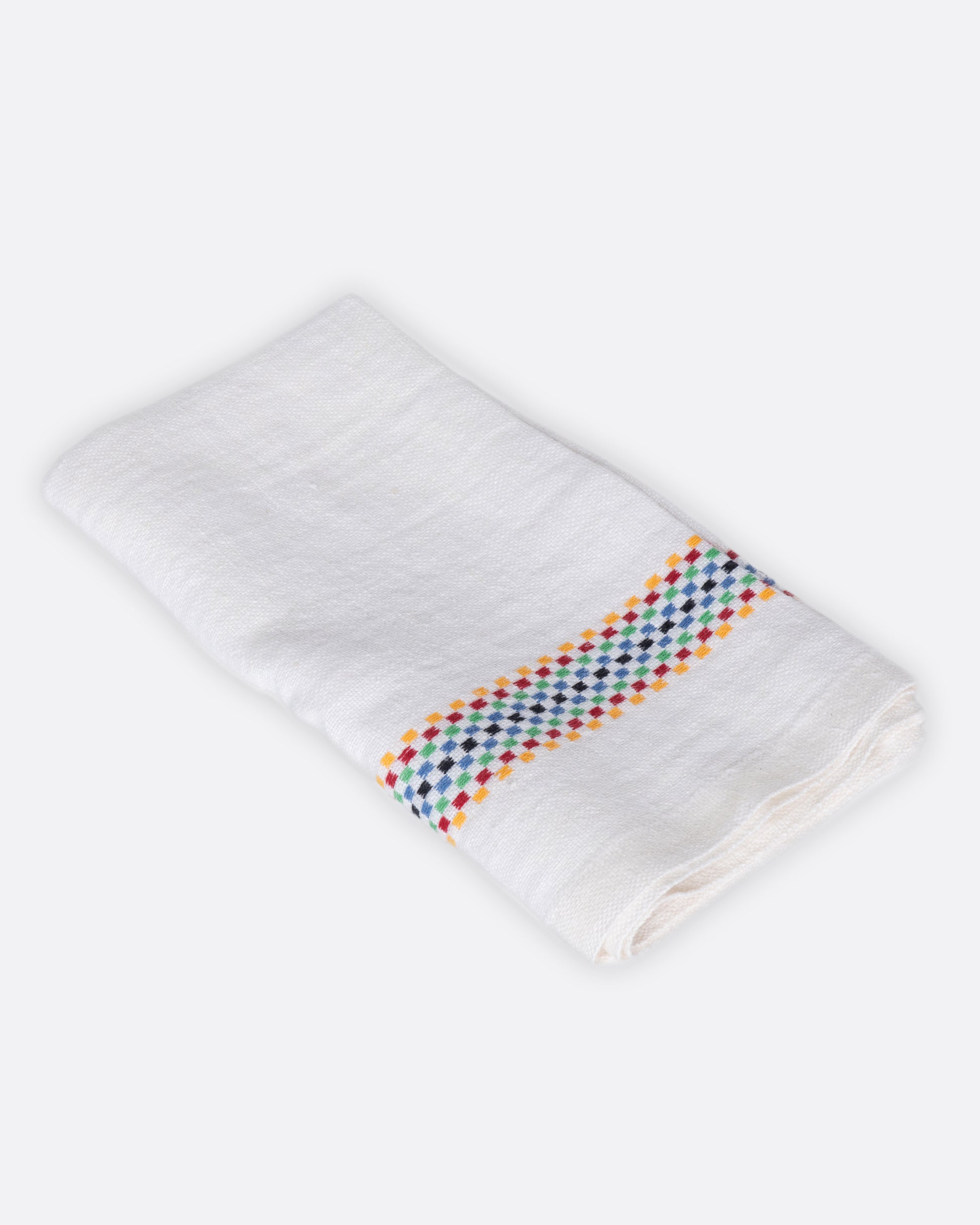 A white linen napkin with rainbow checkered embroidered stripes