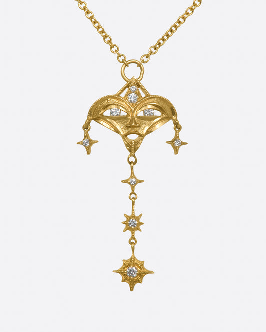 A yellow gold necklace with a mask pendant with diamond eyes and various star dangles, shown from the front.