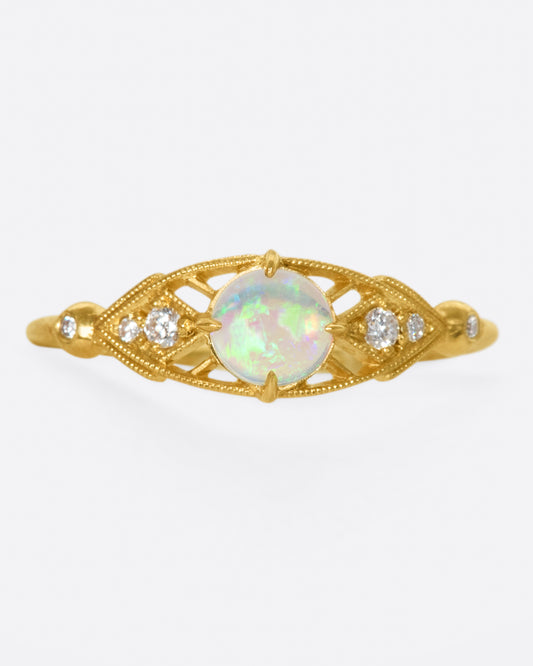 A glowy opal flanked with tiny, sparkly, diamonds, and set on a delicate band 14k gold band
