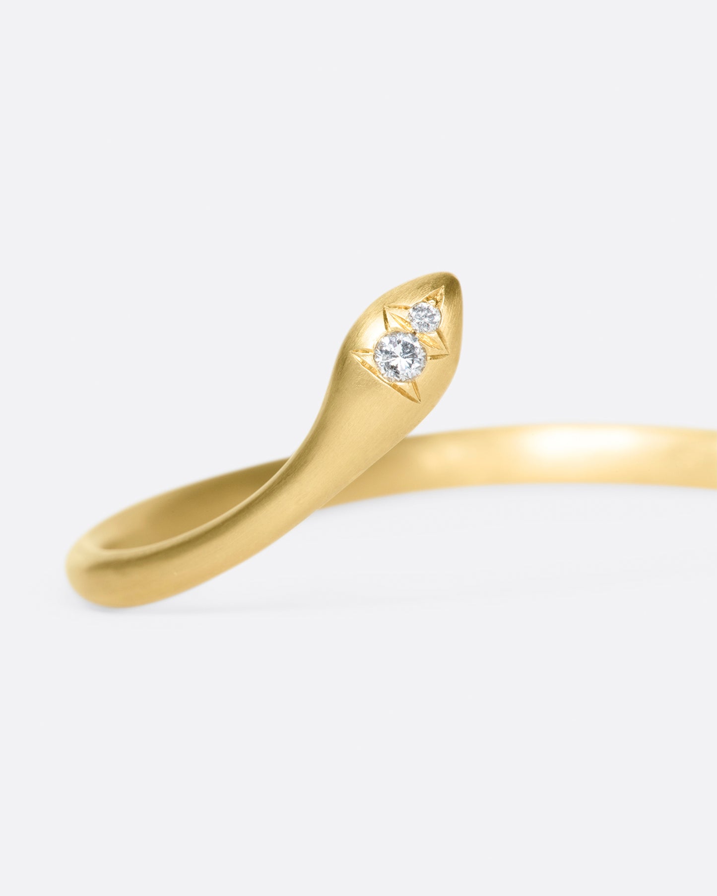 Almost snake-like in shape and gesture, this open cuff bracelet is solid and punctuated with gray diamonds.