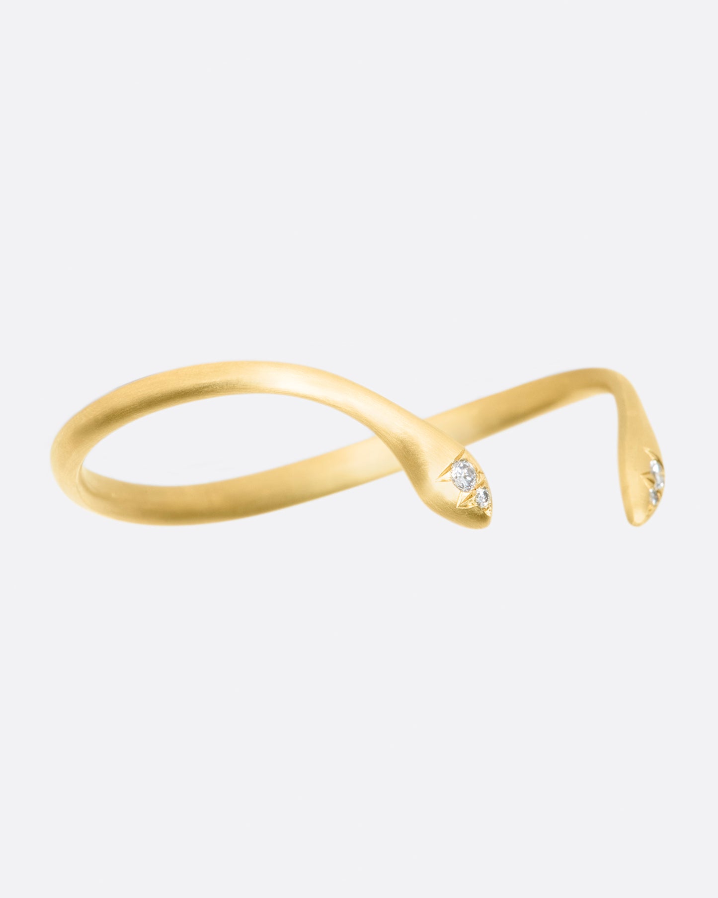 Almost snake-like in shape and gesture, this open cuff bracelet is solid and punctuated with gray diamonds.