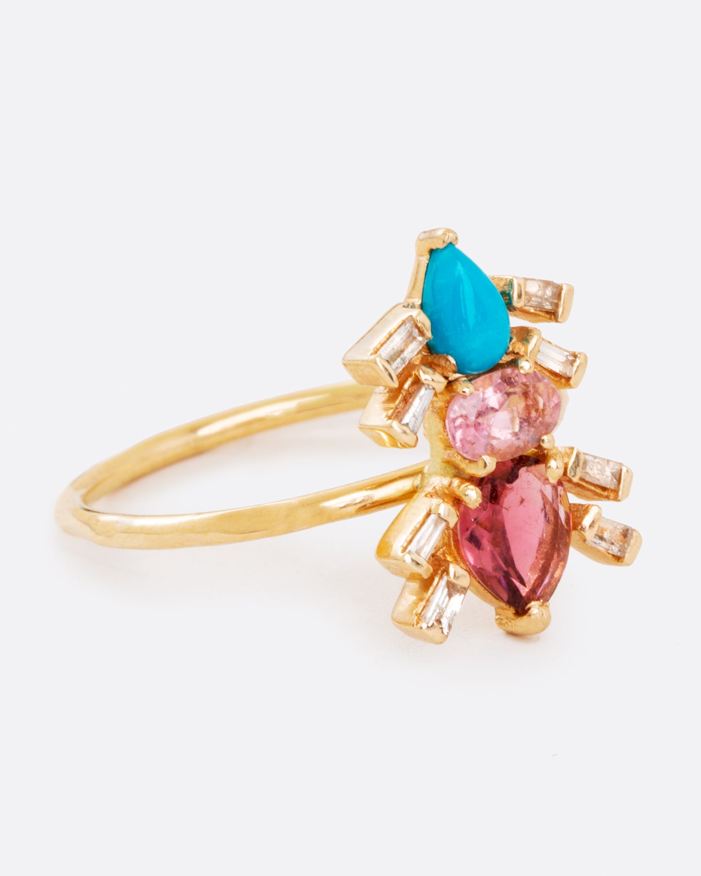A yellow gold ring pink tourmalines, turquoise, and baguette diamonds in the shape of an ant. Shown from the side.