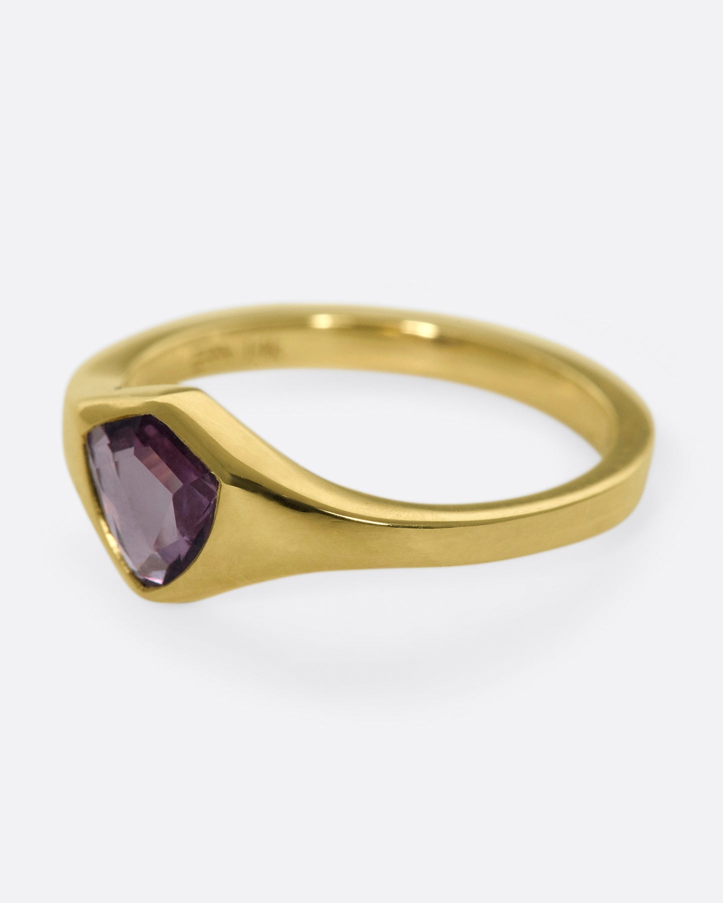 A classic, polished gold signet ring with a burgundy sapphire at its center.