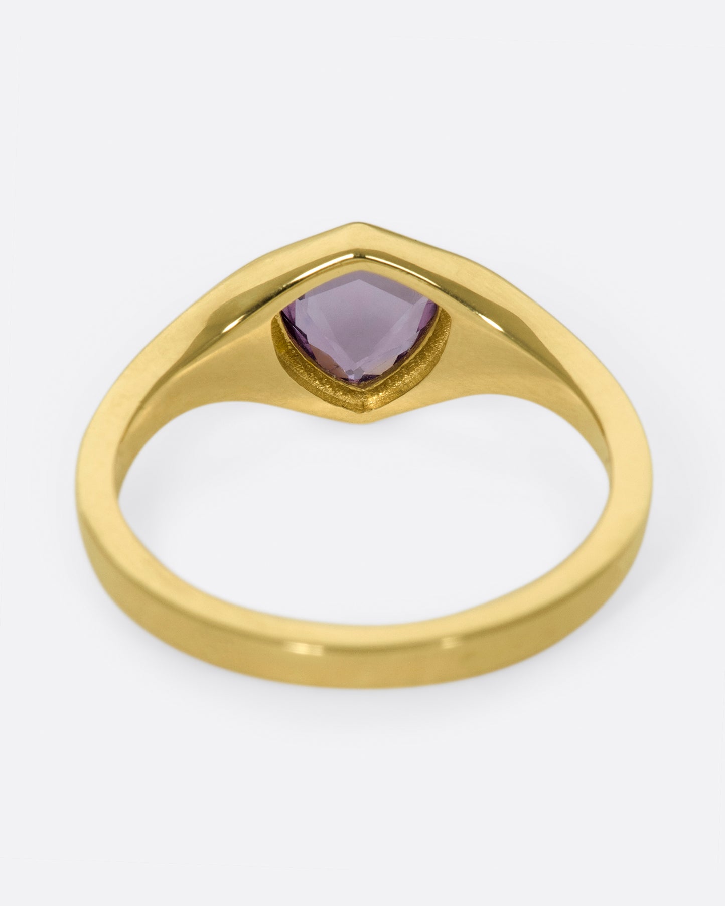 A classic, polished gold signet ring with a burgundy sapphire at its center.