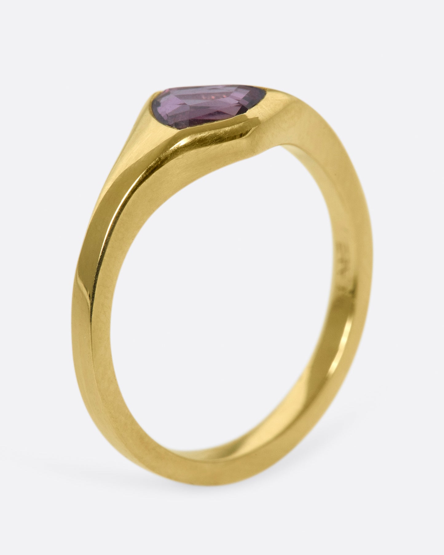 A classic, polished gold signet ring with a burgundy sapphire at its center.