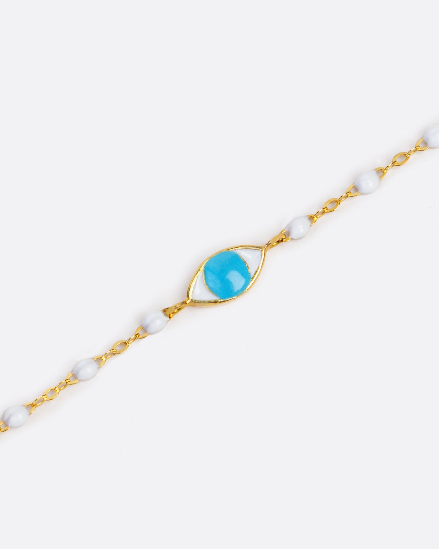 Yellow gold bracelet dipped in white resin, to create a beaded effect. In the middle is an eye charm with a blue resin iris.