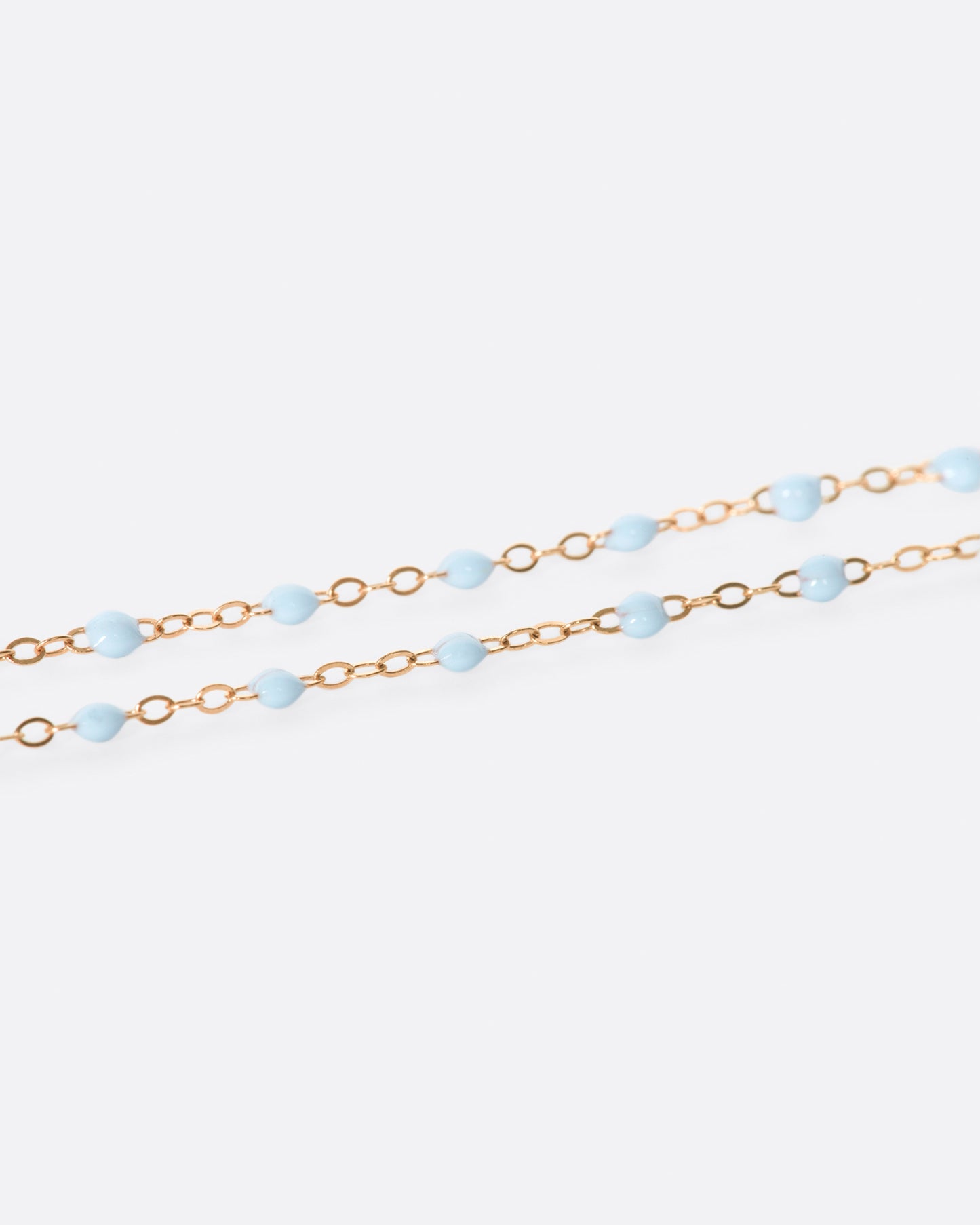 A thin rose gold chain necklace with resin beads. Each necklace is hand dipped in melted resin to create the beaded effect.
